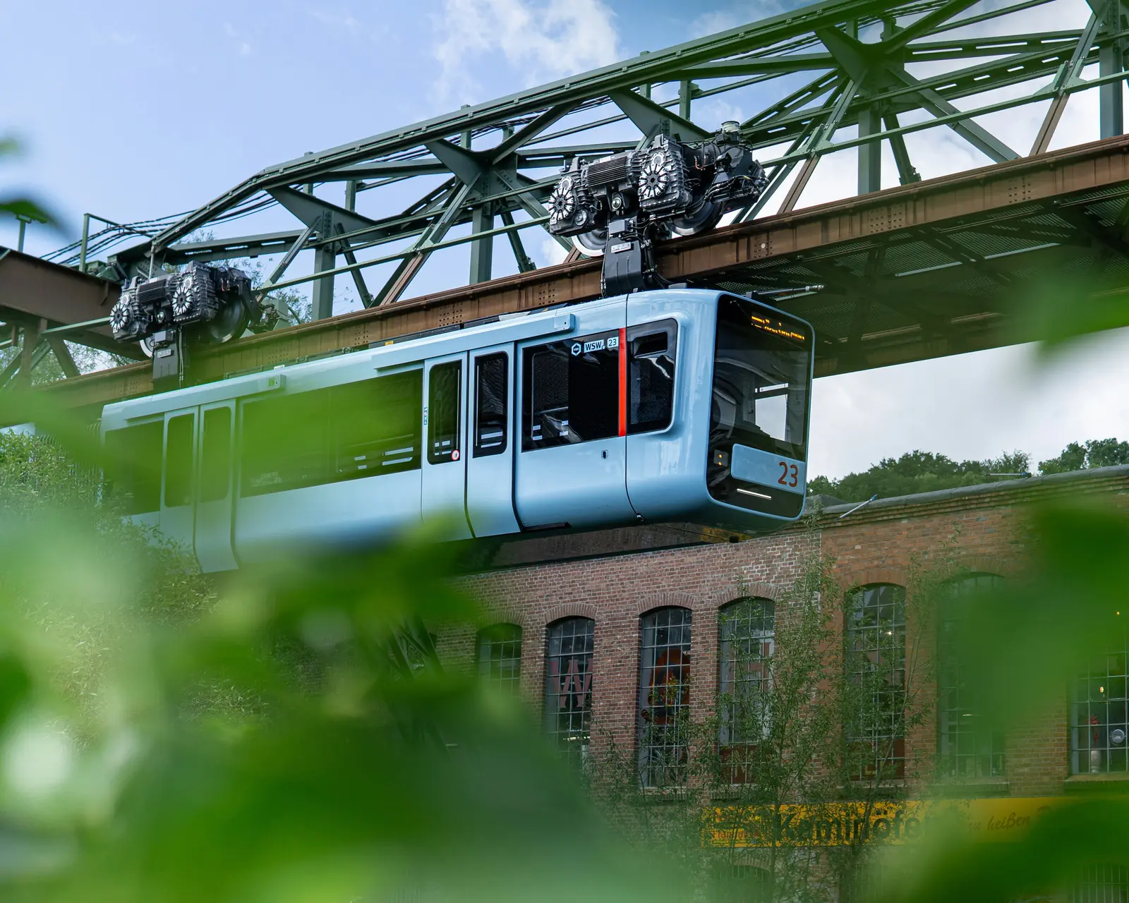Wagen der Wuppertaler Schwebebahn unter dem stählernen Fahrgerüst.