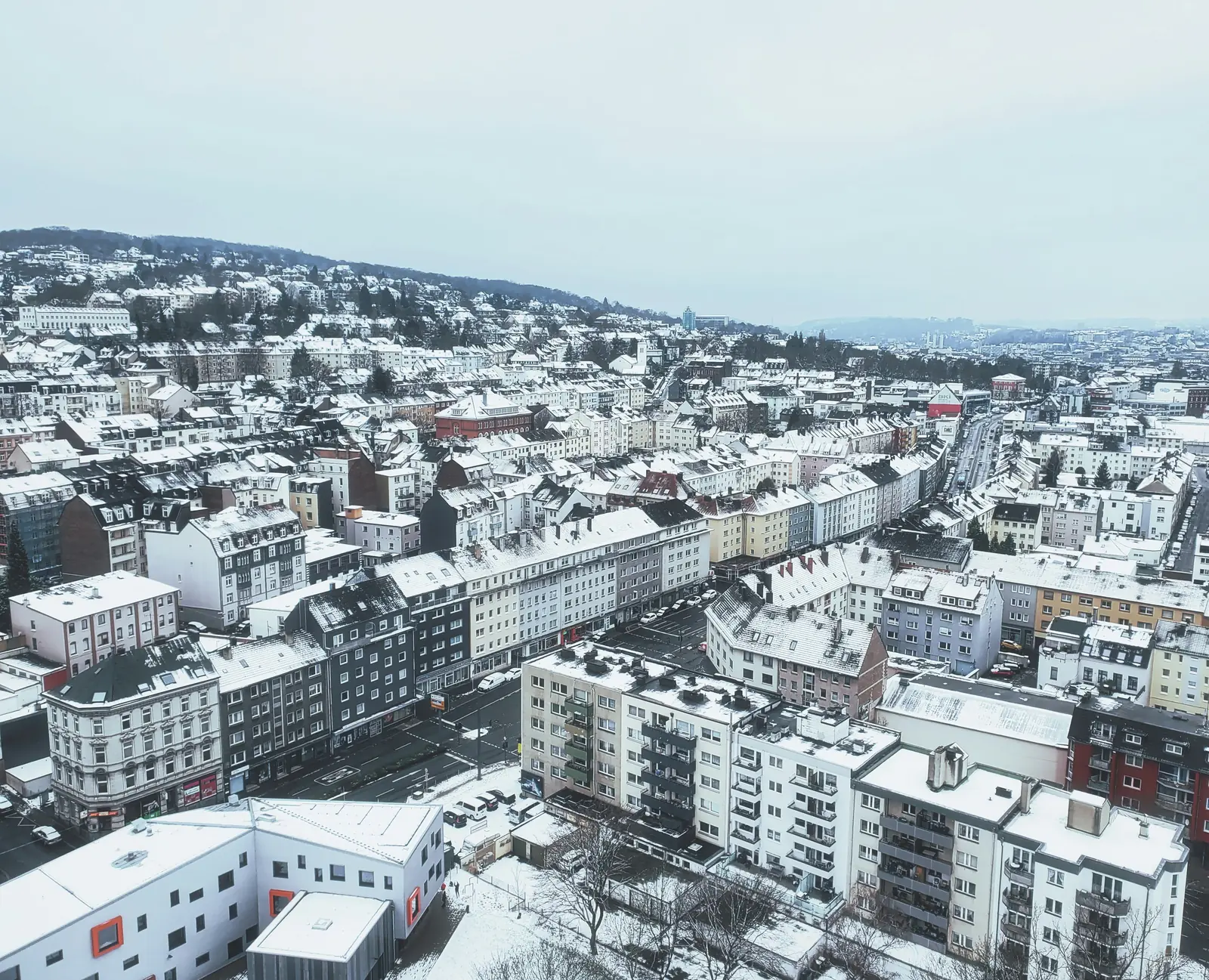 Verschneite Dächer von Wuppertal mit dicht bebauten Wohnstraßen im Winter.
