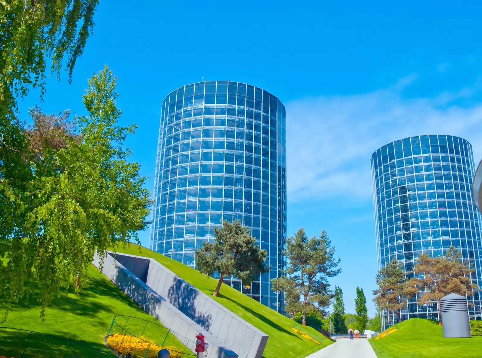 Gläserne Autotürme der Autostadt in Wolfsburg hinter grünem Parkgelände.