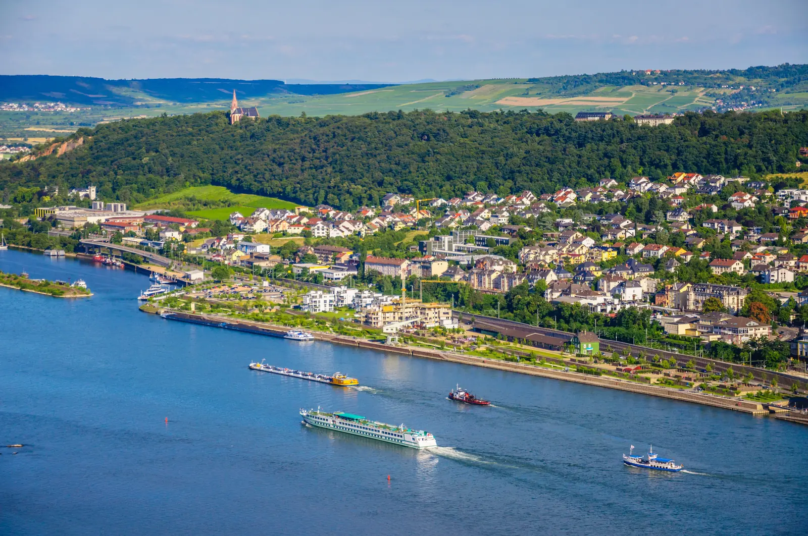 Bingen am Rhein mit Ausflugsschiffen auf dem Fluss und Weinbergen dahinter.