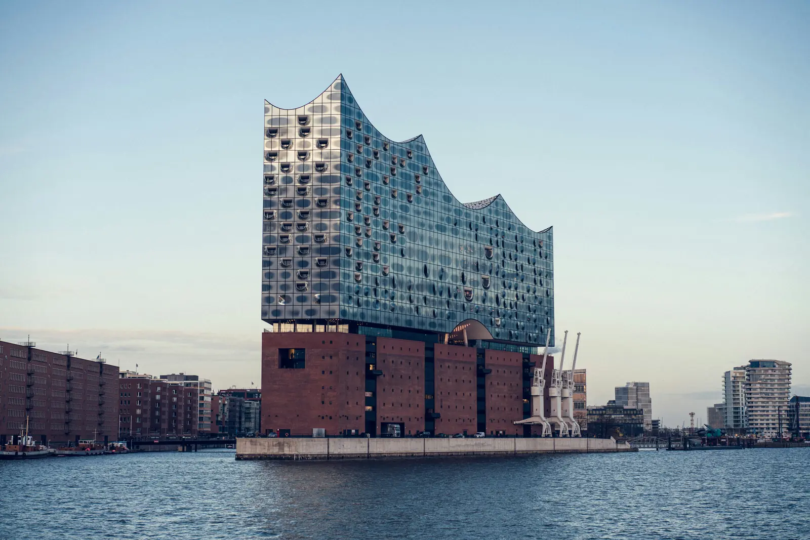 Elbphilharmonie in Hamburg mit Glasaufbau auf dem Backsteinsockel von der Elbe aus.