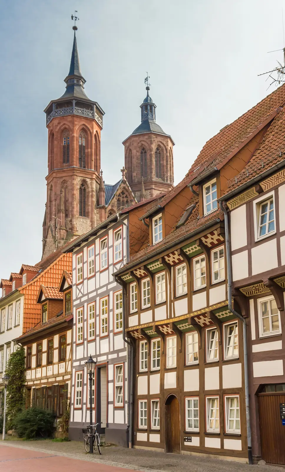 Bunte Fachwerkhäuser in Göttingen, dahinter die Türme der Johanniskirche.