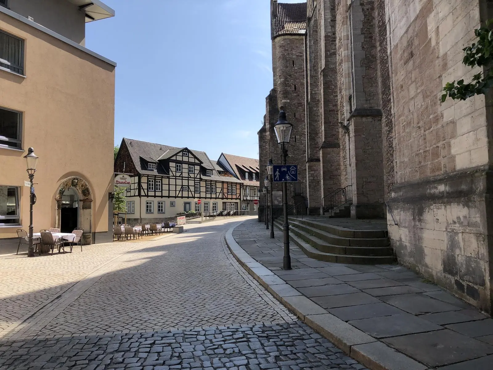 Gepflasterte Gasse in der Braunschweiger Altstadt neben einer Kirche mit Fachwerkhäusern.