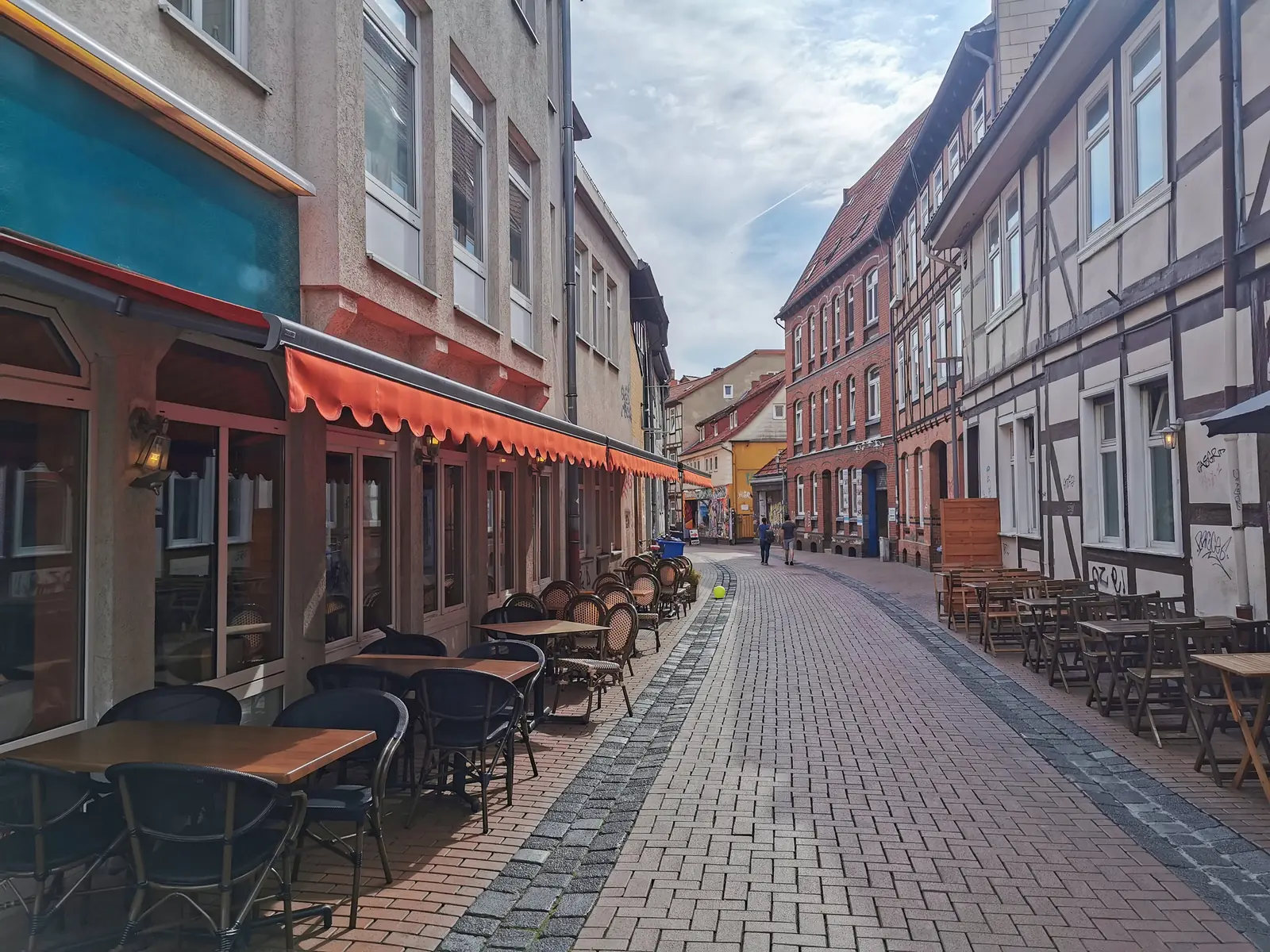 Gepflasterte Gasse in Göttingen mit Außengastronomie und Fachwerkfassaden.