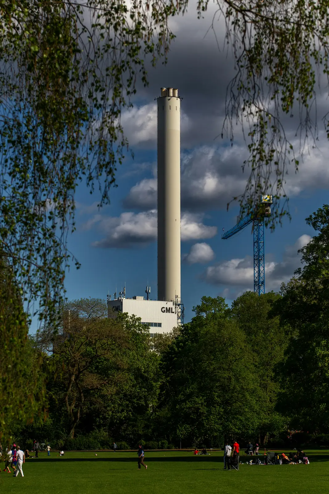 Hoher Schornstein des Müllheizkraftwerks GML über einer Parkwiese in Ludwigshafen.