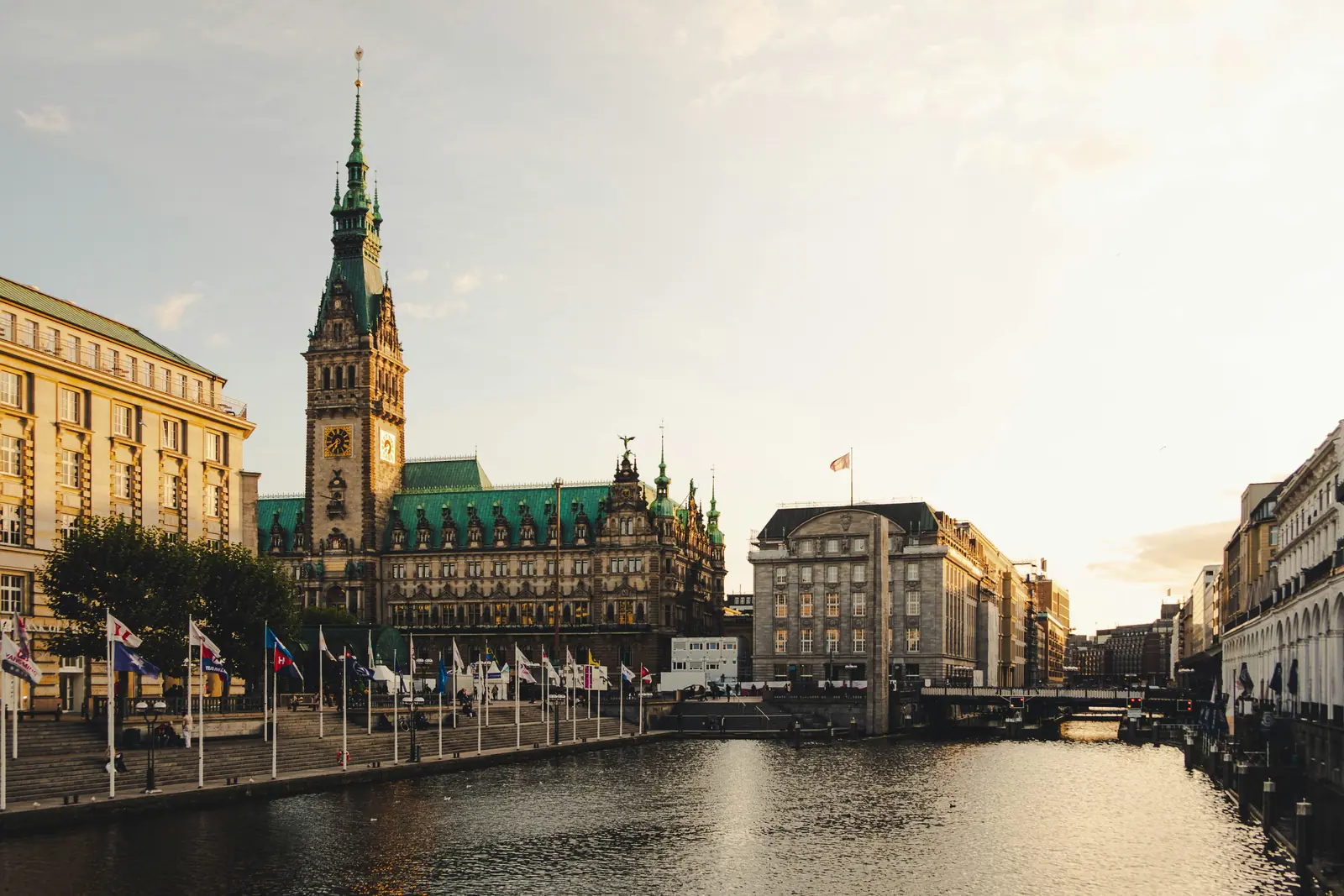 Hamburger Rathaus mit Turm an der Kleinen Alster im Abendlicht.