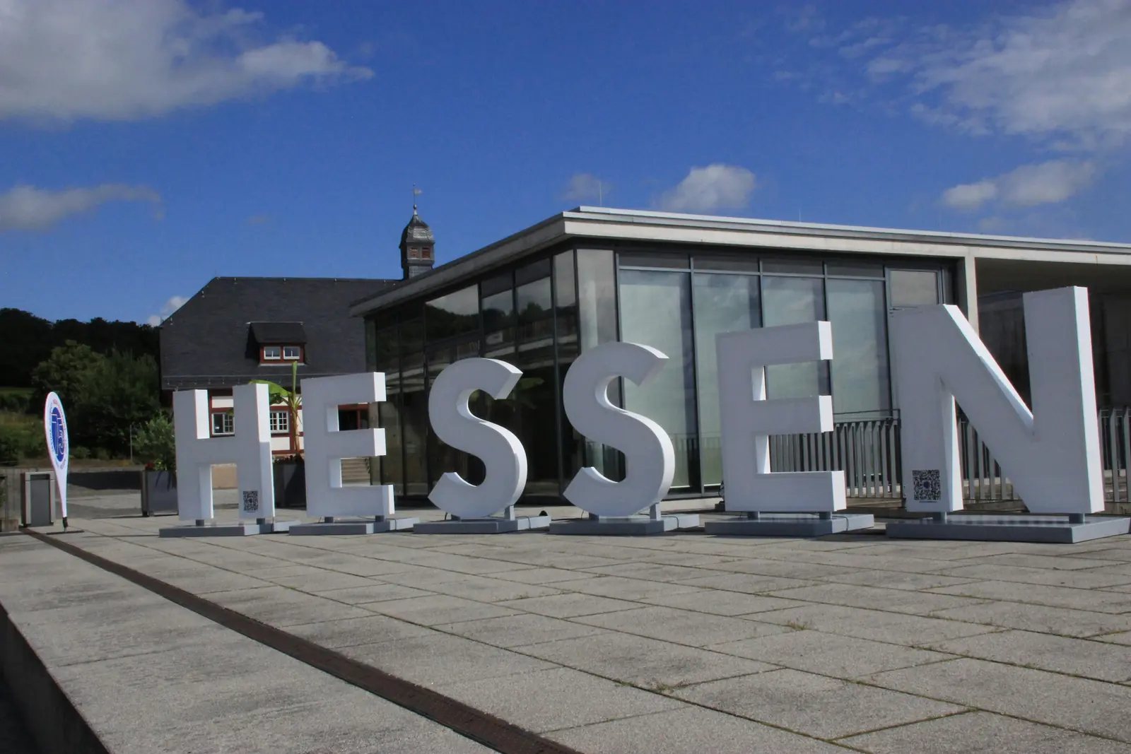 Große Buchstaben mit dem Schriftzug HESSEN vor einem modernen Glasgebäude.