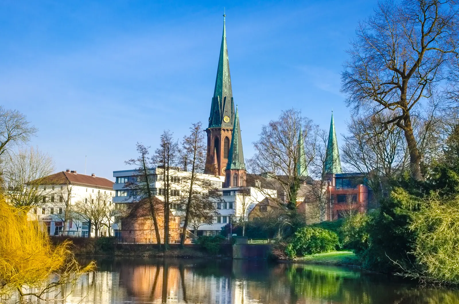 Türme der Lambertikirche in Oldenburg über dem Schlossteich im Winter.
