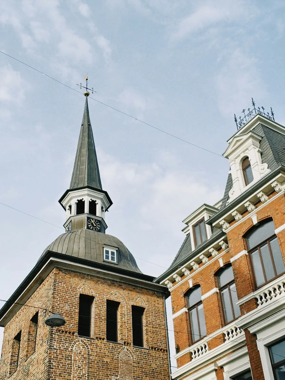 Lappan in Oldenburg, gotischer Backsteinturm mit Haube, neben einer Gründerzeitfassade.