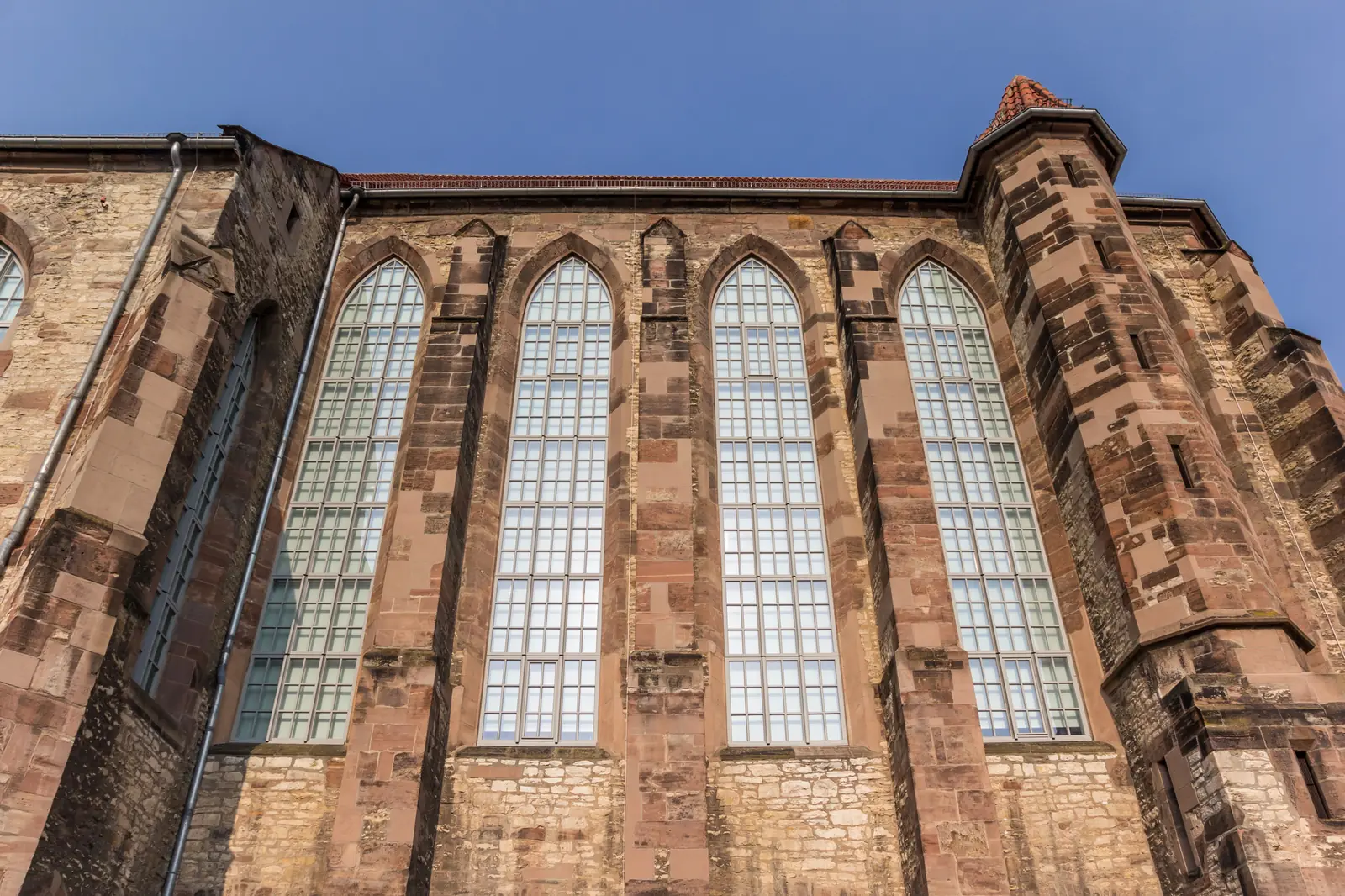 Paulinerkirche in Göttingen mit hohen gotischen Fenstern vor blauem Himmel.