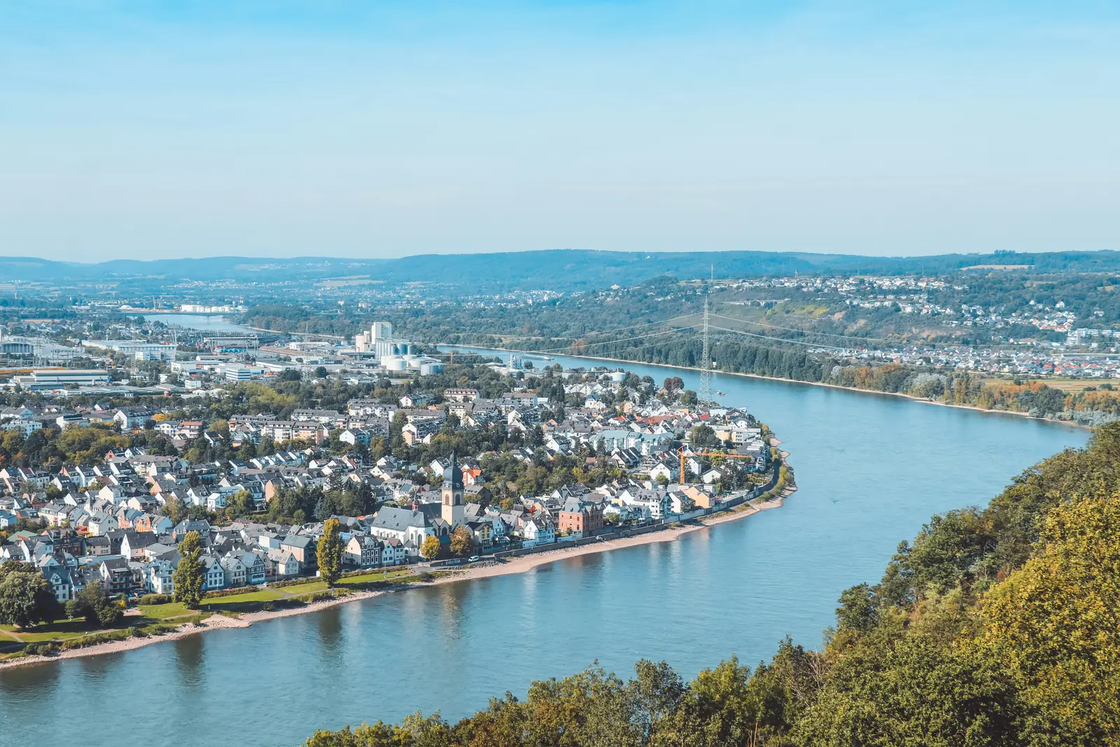 Blick von der Höhe auf den Rhein bei Koblenz mit Wohnbebauung am Ufer.