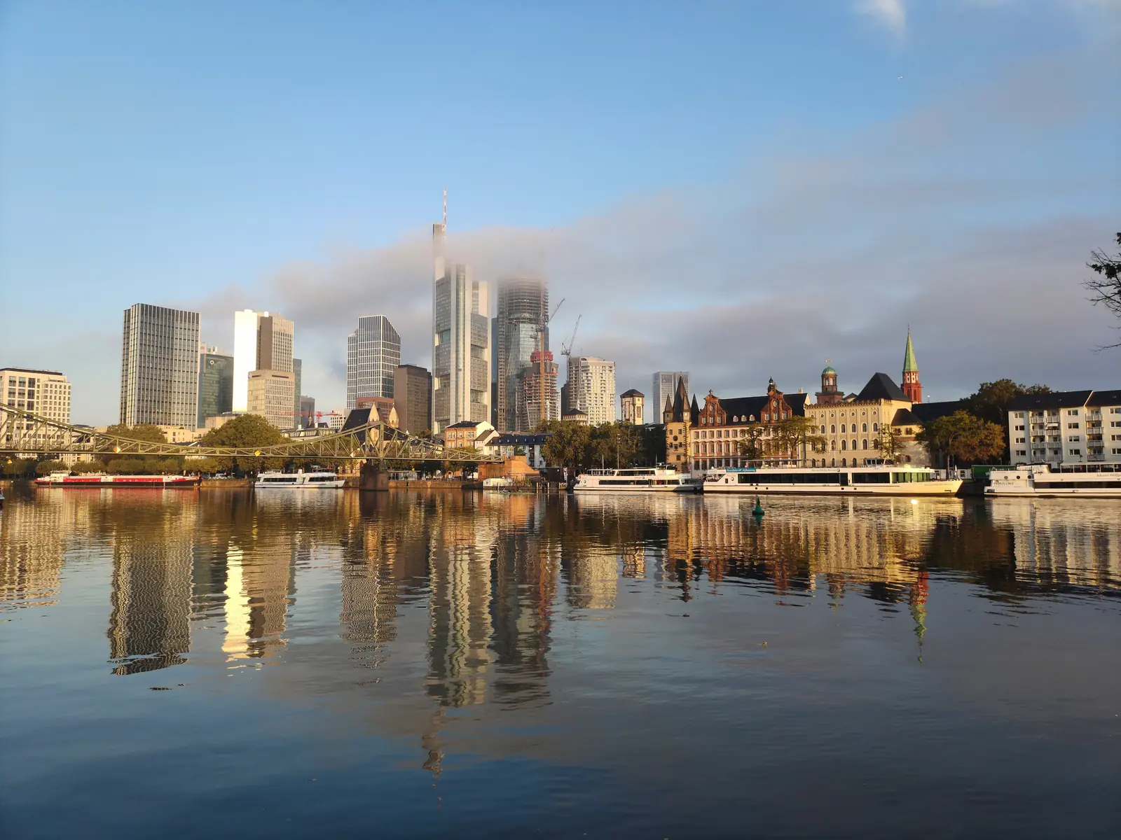 Wolkenverhangene Skyline von Frankfurt am Main mit Eisernem Steg im Morgenlicht.