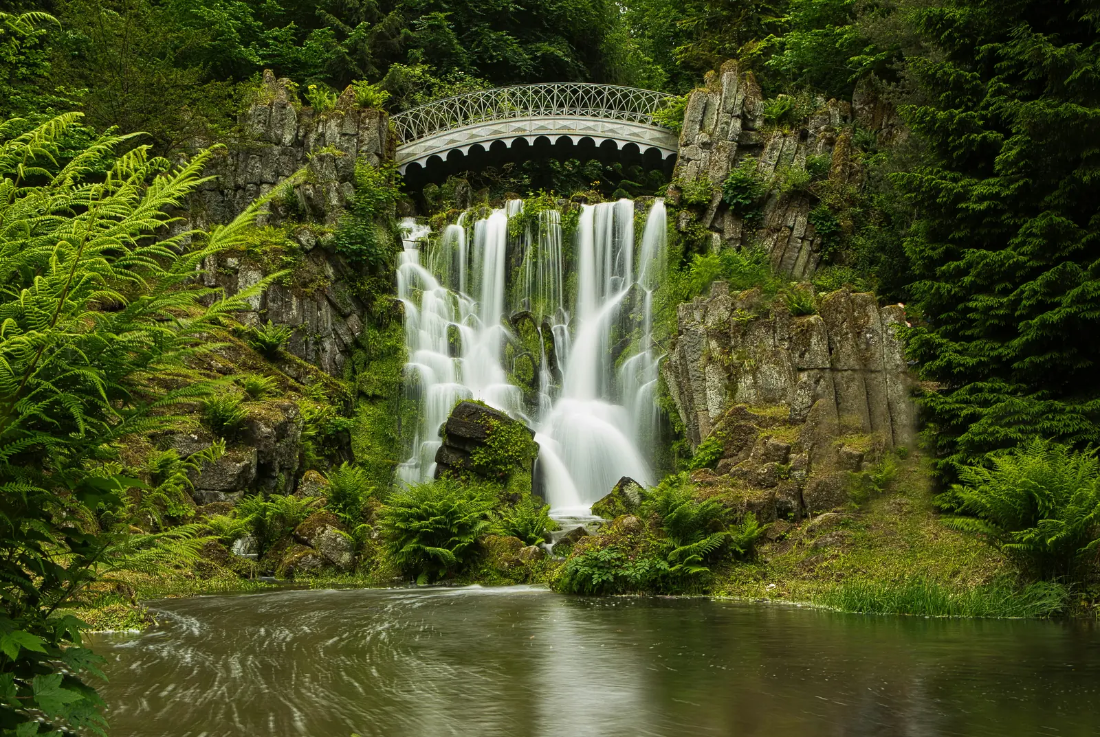 Wasserfall an der Teufelsbrücke im Bergpark Wilhelmshöhe zwischen bemoosten Felsen.