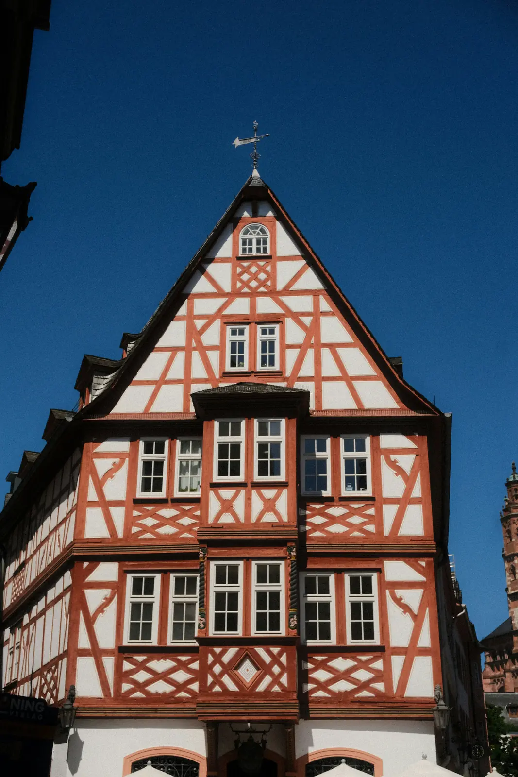 Fachwerkgiebel des Weinhauses zum Spiegel am Leichhof in Mainz vor blauem Himmel.