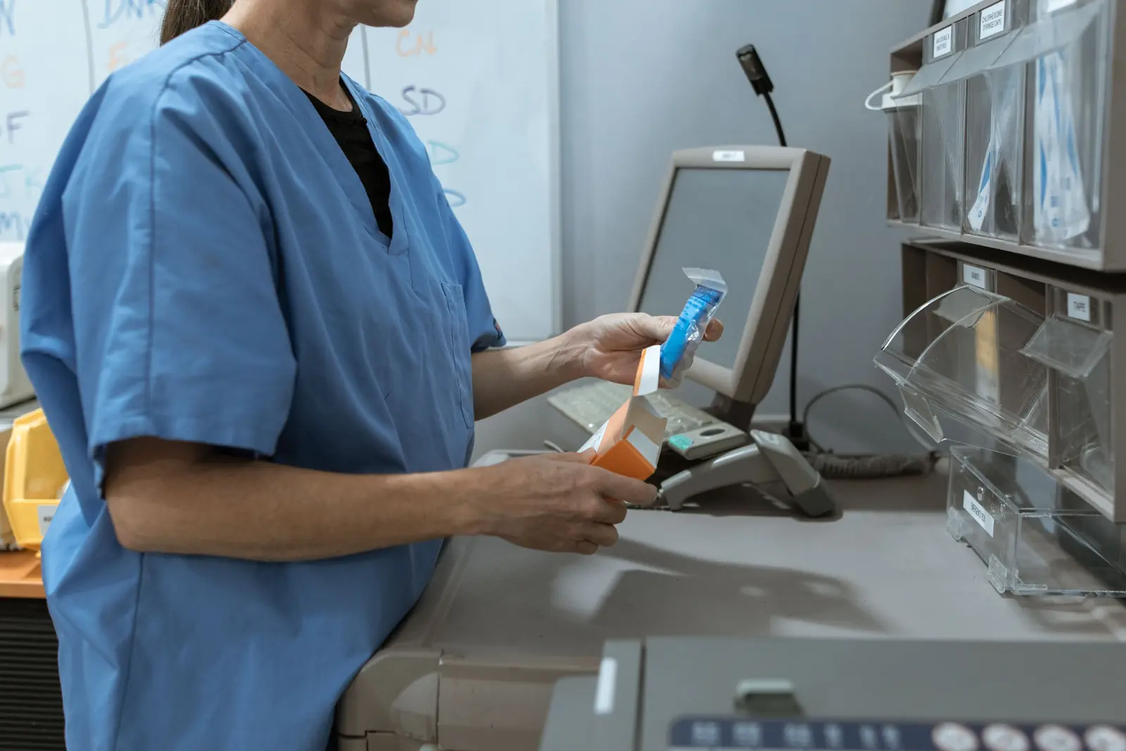 Betriebsmittelprüfung in der Apotheke: Mitarbeiterin am Kommissionierautomaten.