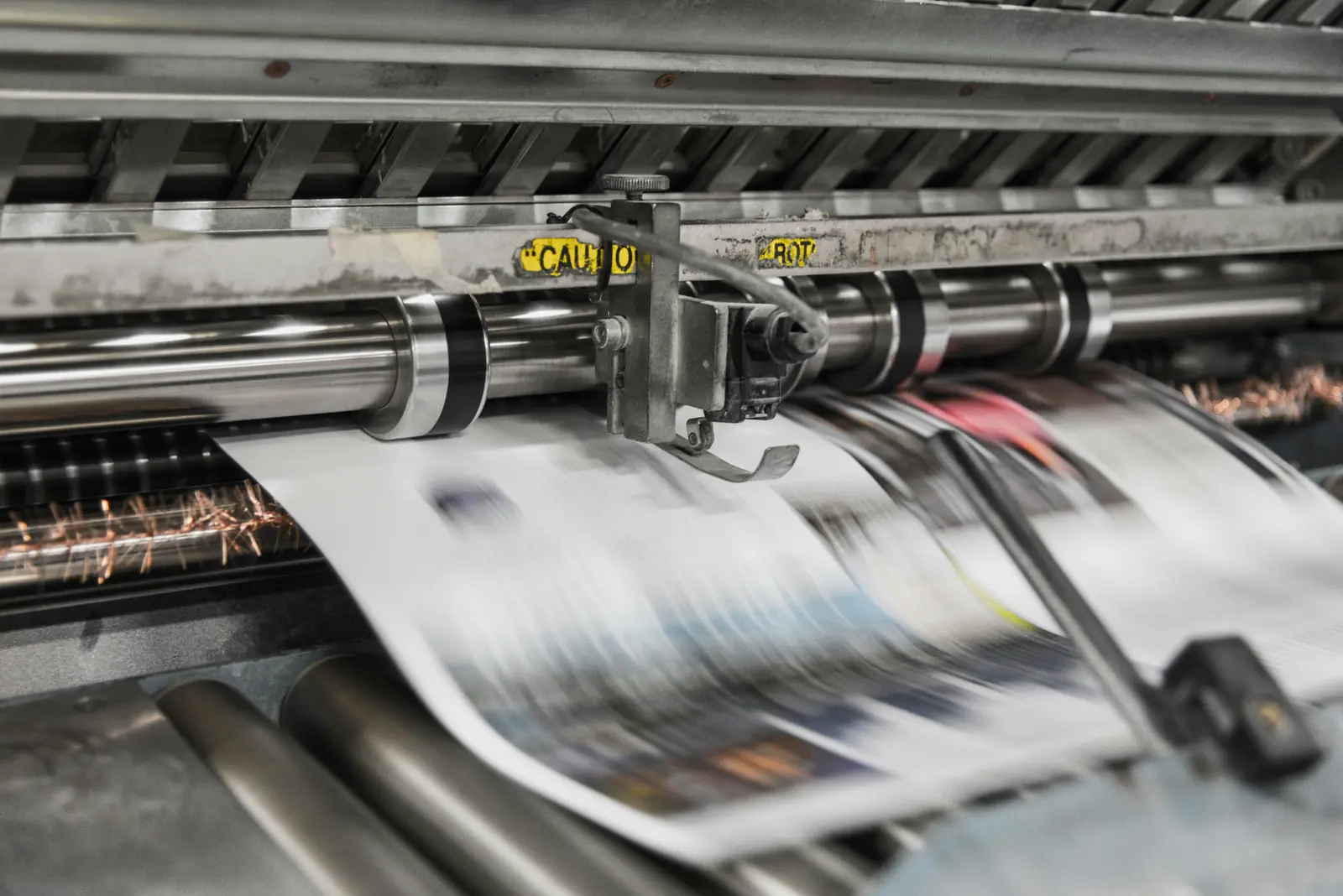 Betriebsmittelprüfung in der Druckerei: Bedruckte Bogen laufen durch die Druckmaschine.