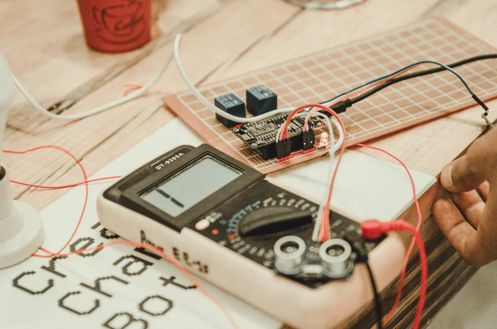 Betriebsmittelprüfung im Einkaufszentrum: Multimeter und Steuerplatine auf dem Werktisch.