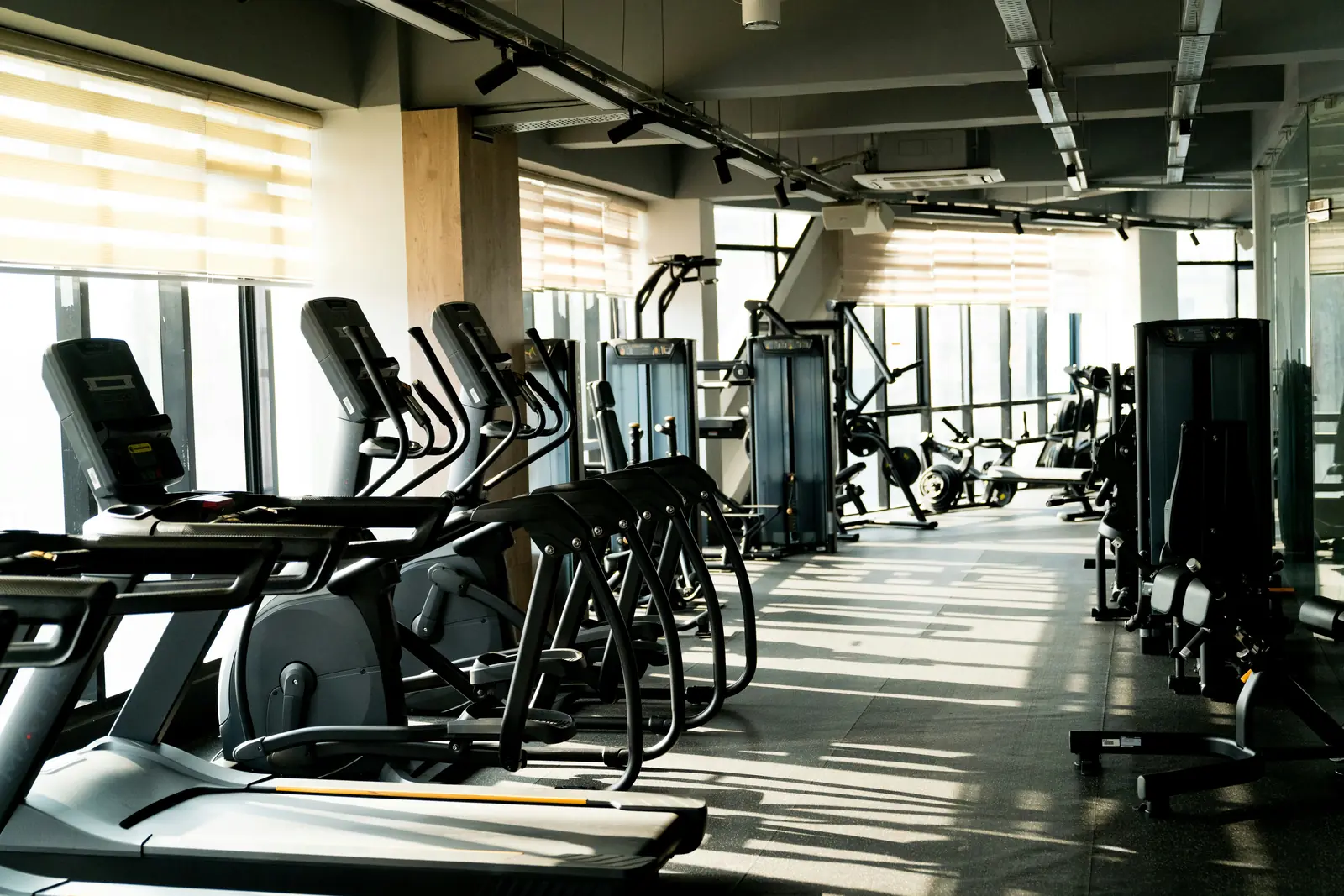 Betriebsmittelprüfung im Fitnessstudio: Laufbänder und Crosstrainer an der Fensterfront.