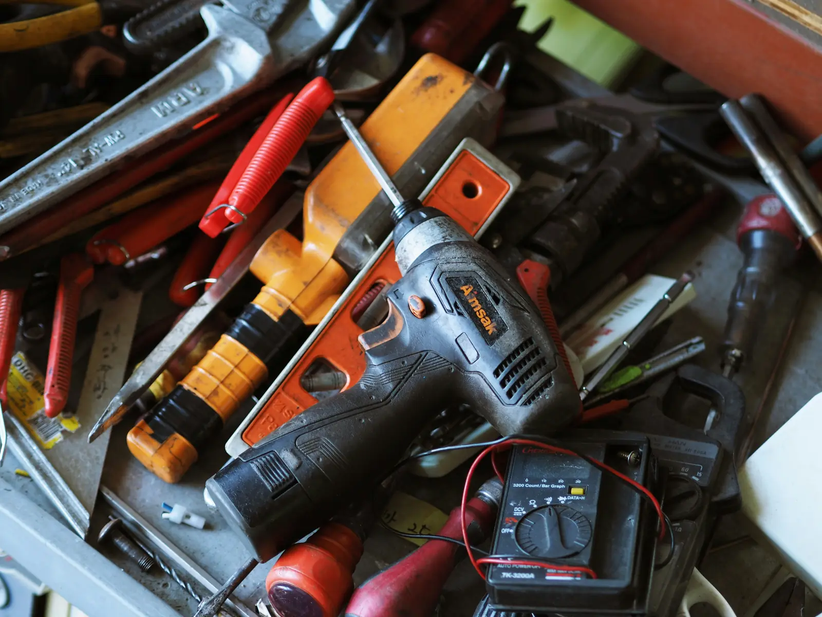 Betriebsmittelprüfung im Handwerksbetrieb: Bohrmaschine und Multimeter im Werkzeugkasten.