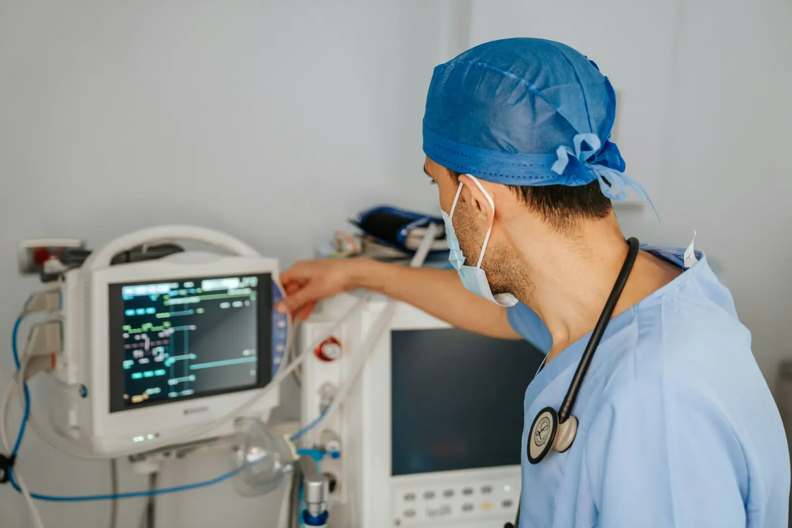 Betriebsmittelprüfung im Krankenhaus: Arzt bedient einen Patientenmonitor am Gerätewagen.