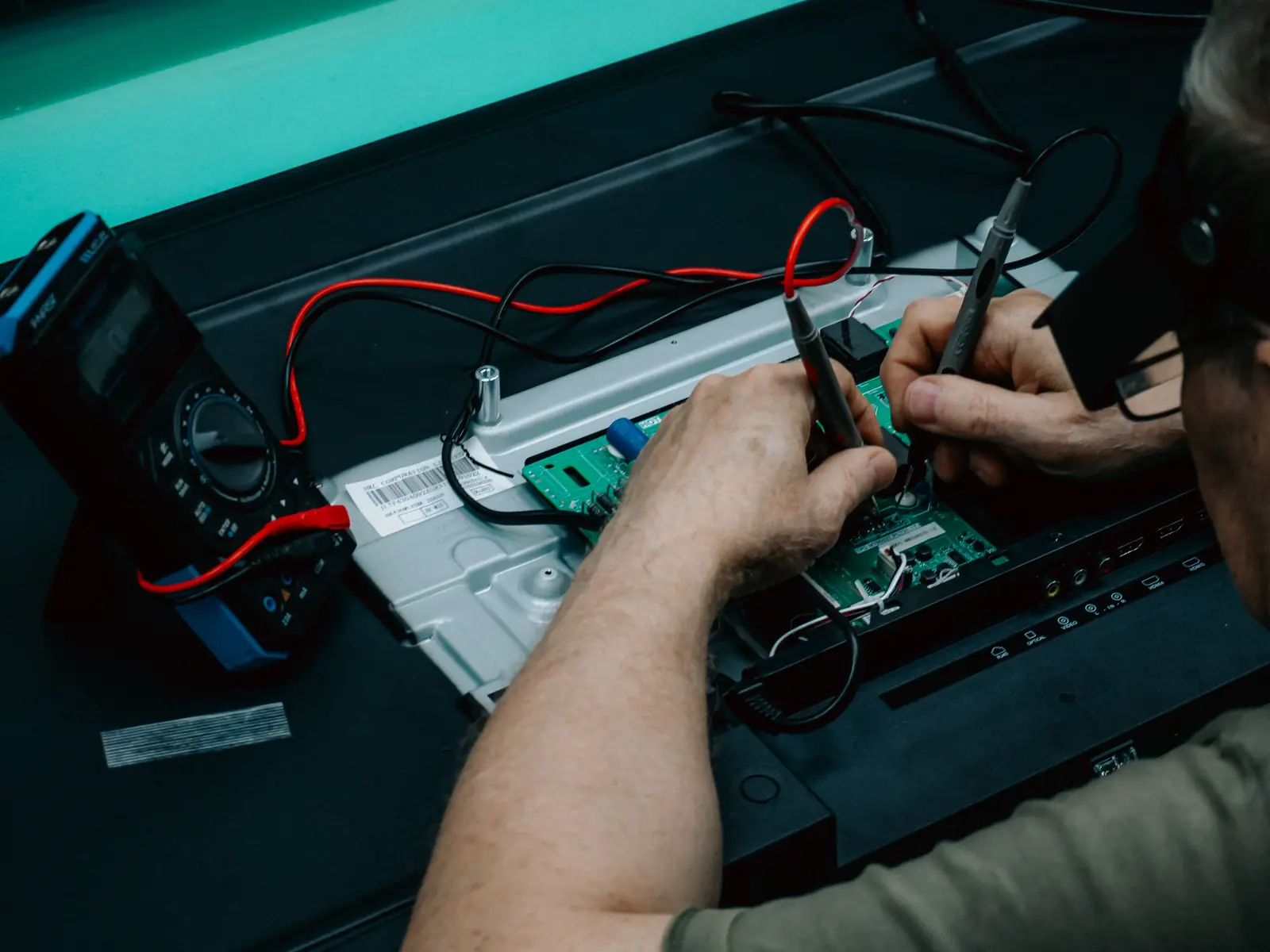 Betriebsmittelprüfung an der Universität: Messung an einer Platine mit Multimeter und Prüfspitzen.