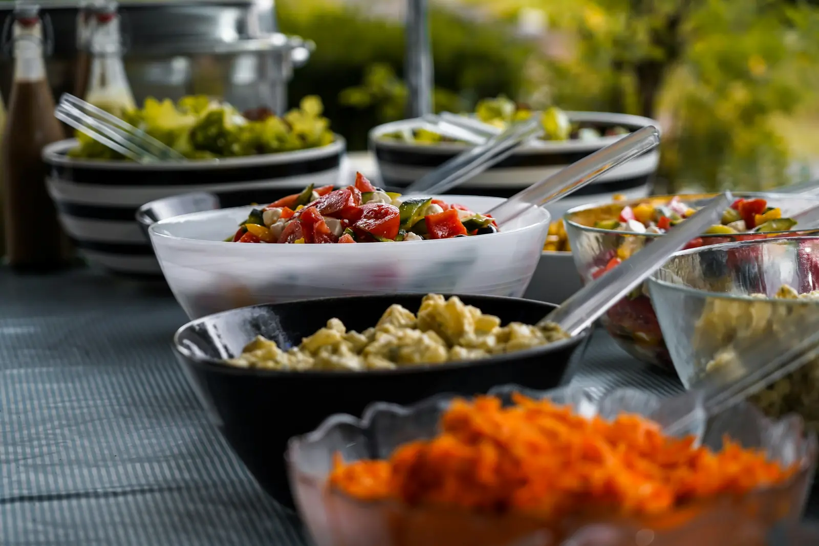 Betriebsmittelprüfung und Leiter- und Trittprüfung im Catering: Salatschüsseln auf einer Buffettafel im Freien.