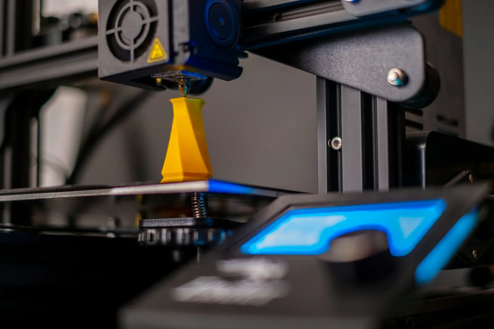 Betriebsmittelprüfung und Leiter- und Trittprüfung in der Druckerei: 3D-Drucker baut ein gelbes Werkstück auf.
