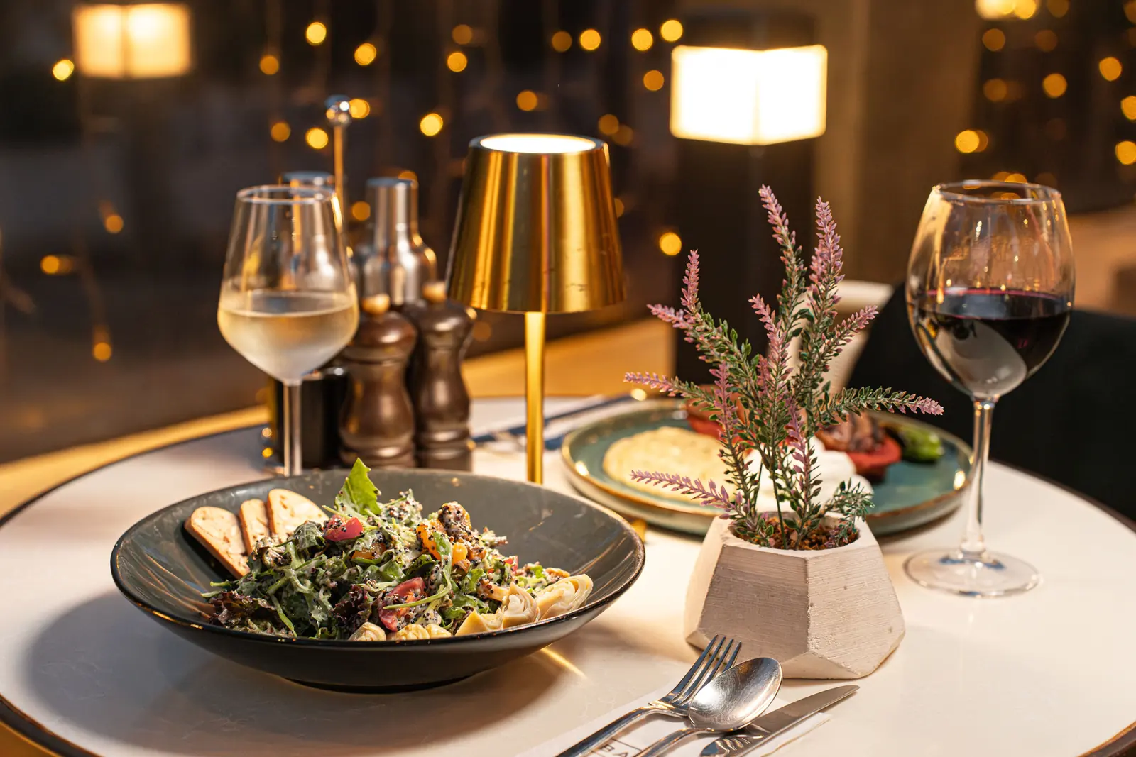 Betriebsmittelprüfung und Leiter- und Trittprüfung in der Gastronomie: Gedeckter Tisch mit Tischleuchte am Abend.