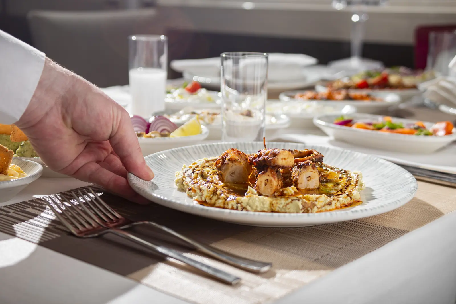 Betriebsmittelprüfung und Leiter- und Trittprüfung in der Gastronomie: Kellner stellt einen Teller auf den Tisch.