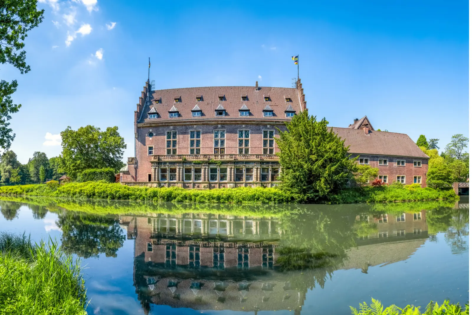Betriebsmittelprüfung und Leiter- und Trittprüfung in Gladbeck: Backsteinschloss mit Dachgauben an der Gräfte.