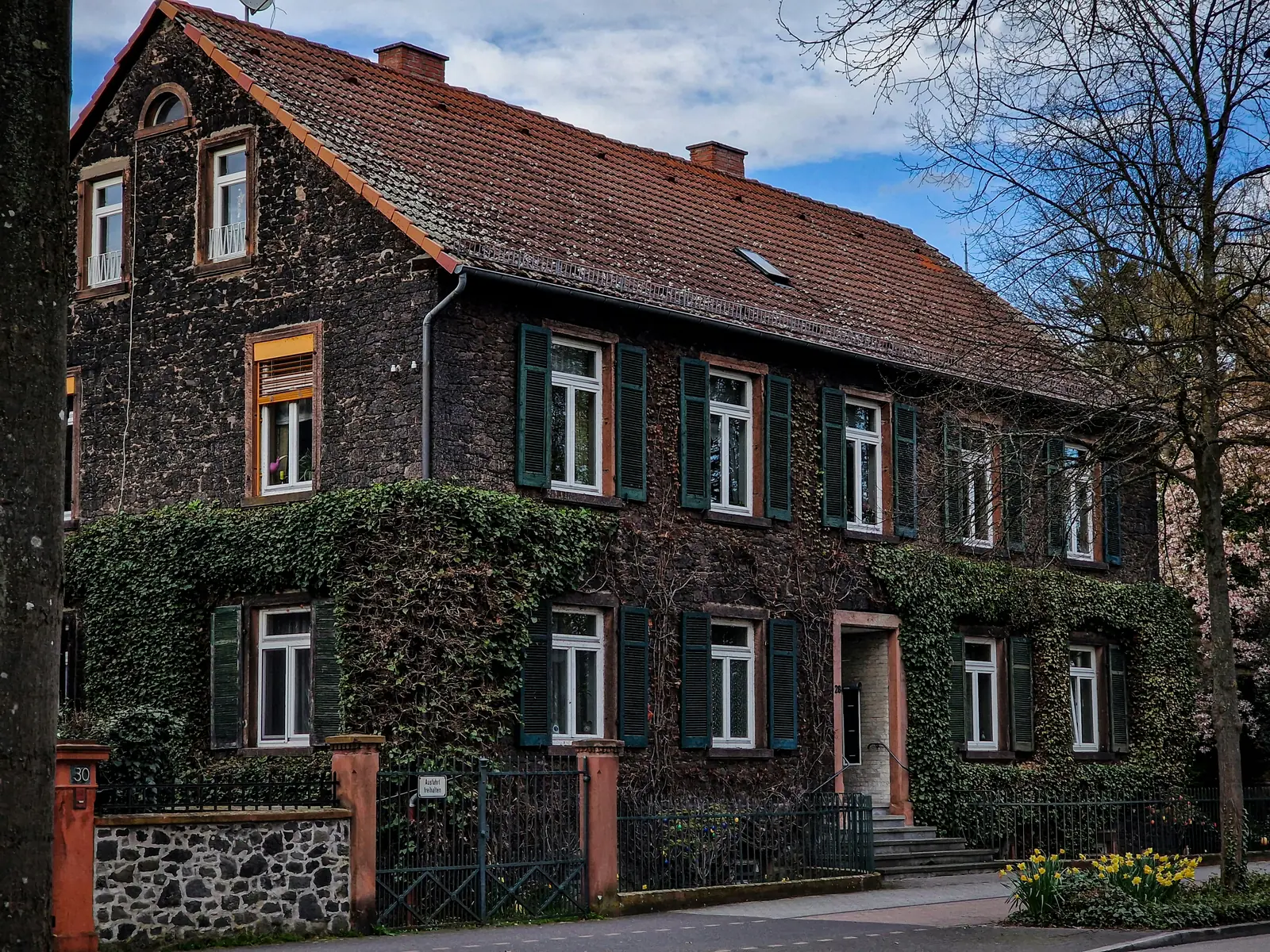 Betriebsmittelprüfung und Leiter- und Trittprüfung in Hanau: Efeubewachsenes Bruchsteinhaus an der Straße.