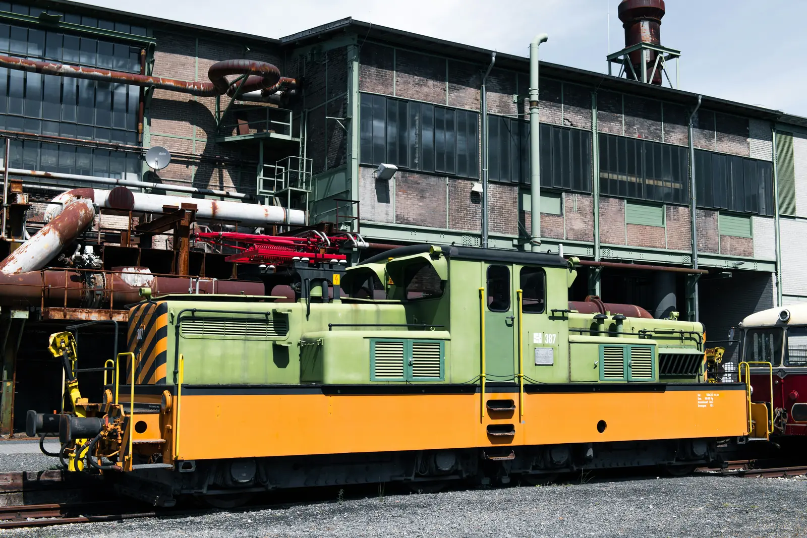 Betriebsmittelprüfung und Leiter- und Trittprüfung in Hattingen: Werkslok vor Rohrleitungen und Werkshalle.