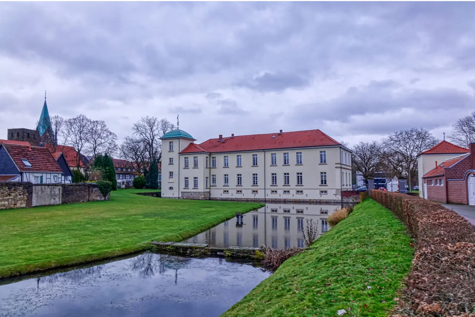 Betriebsmittelprüfung und Leiter- und Trittprüfung in Herten: Herrenhaus am Wassergraben mit Kirchturm.