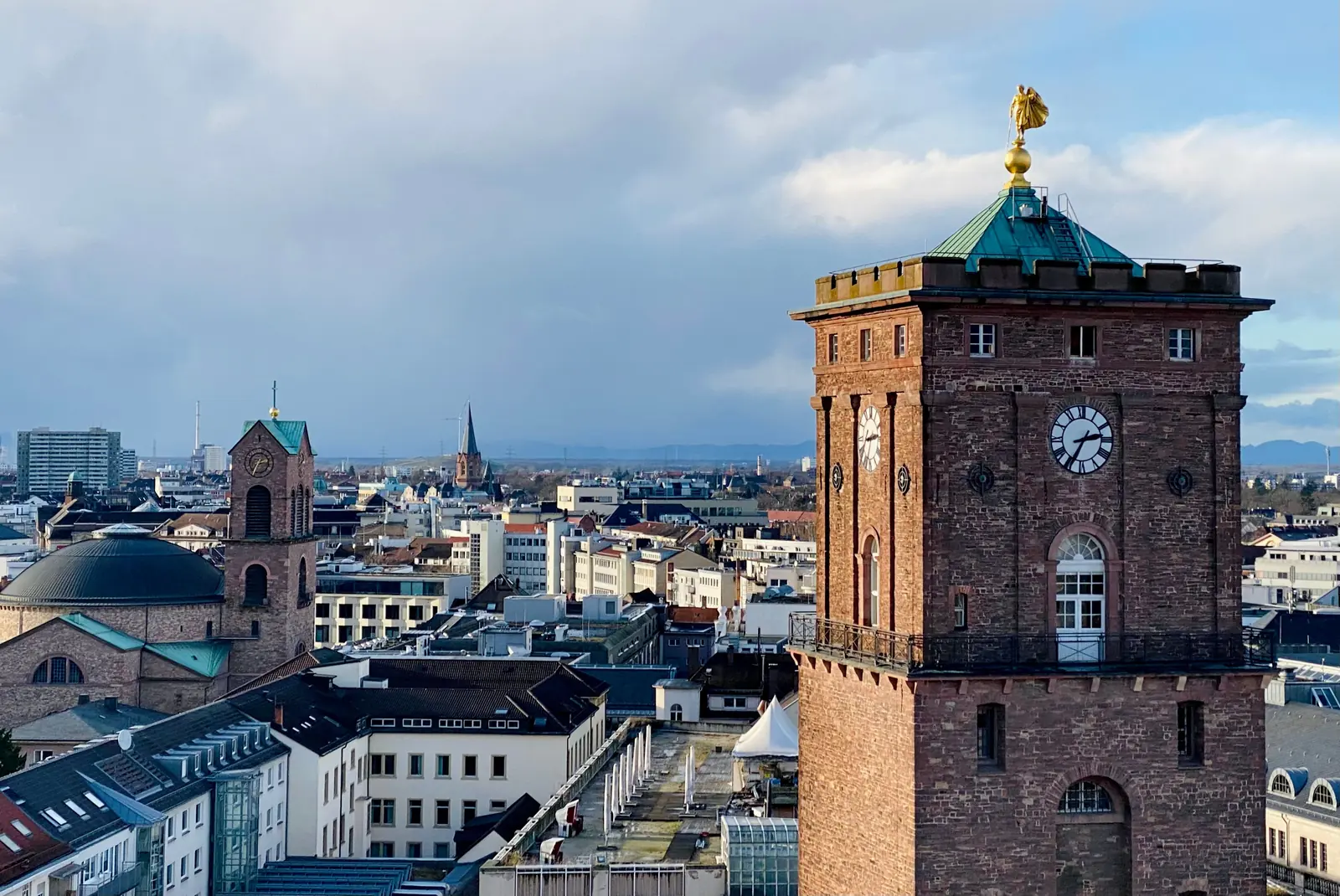 Betriebsmittelprüfung und Leiter- und Trittprüfung in Karlsruhe: Backsteinturm mit Uhr über den Dächern.