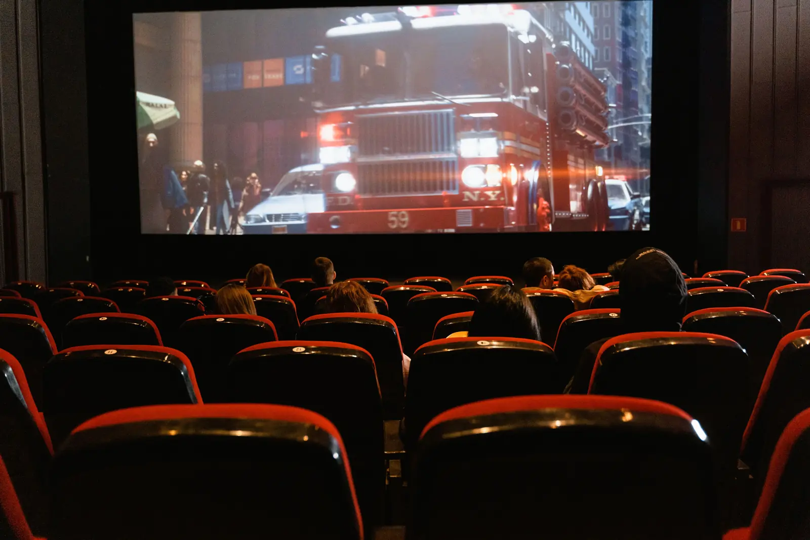 Betriebsmittelprüfung und Leiter- und Trittprüfung im Kino: Zuschauer vor der laufenden Leinwand.