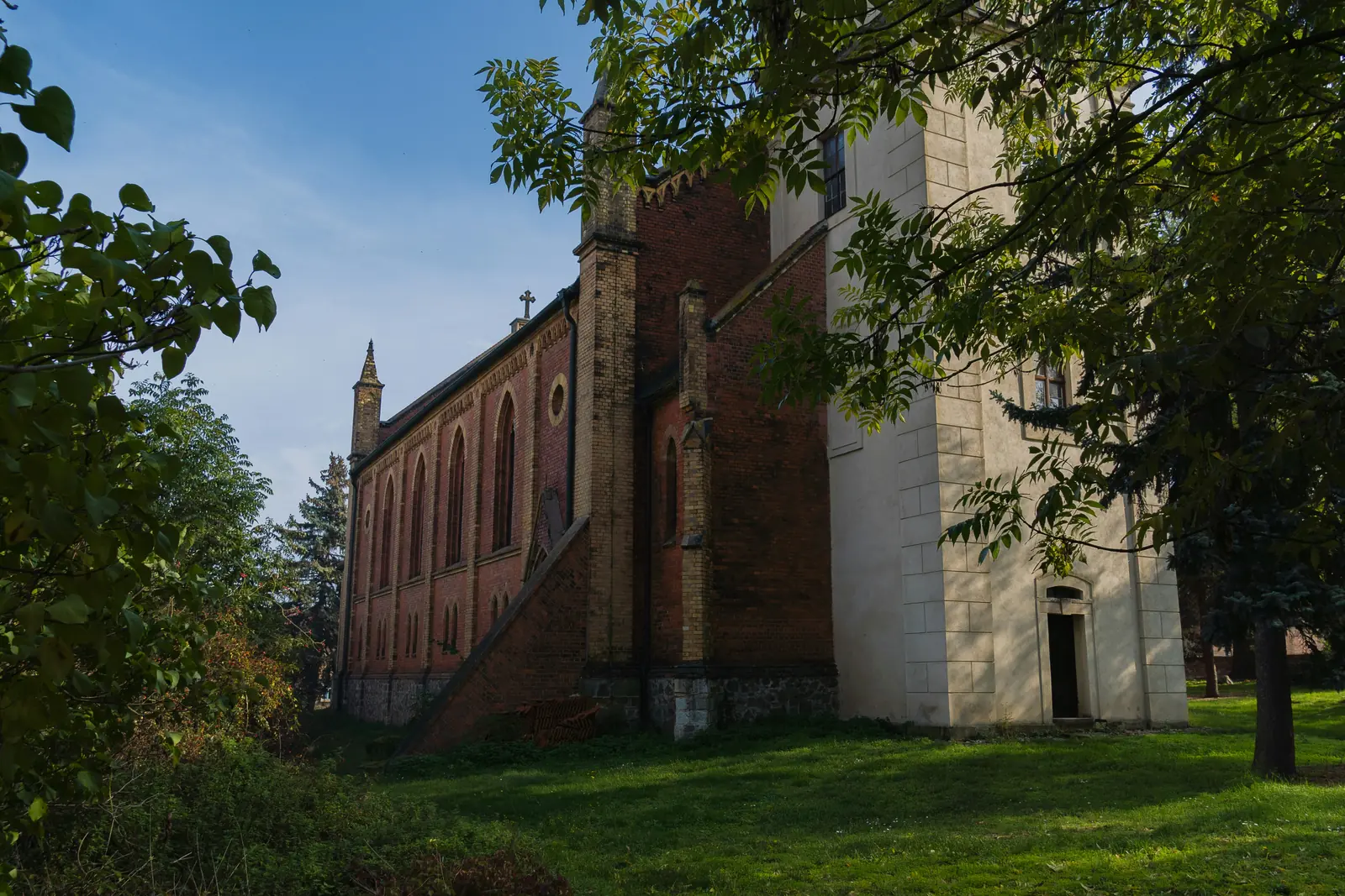 Betriebsmittelprüfung und Leiter- und Trittprüfung in der Kirche: Backsteinkirche mit Strebepfeilern im Grünen.