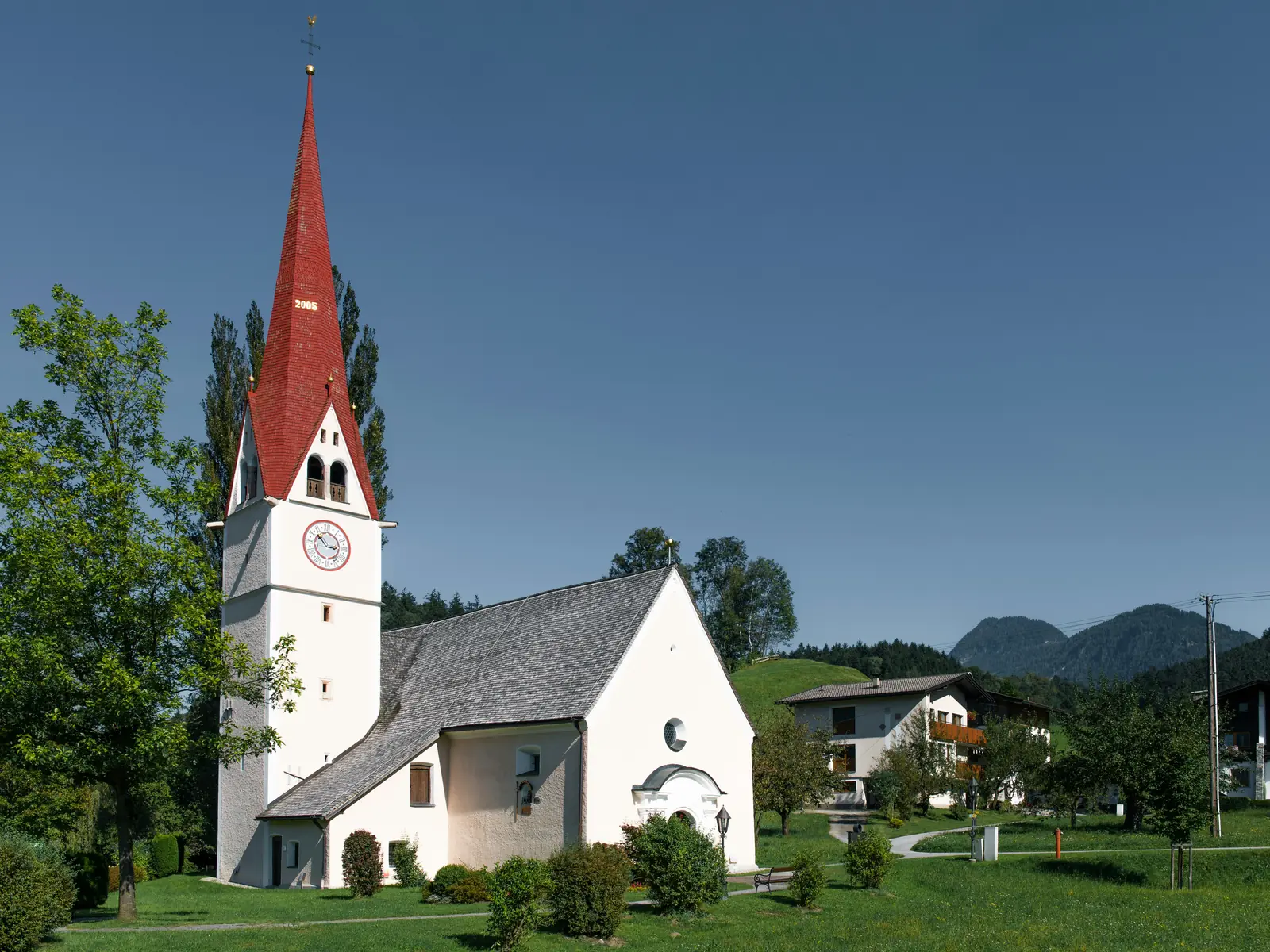 Betriebsmittelprüfung und Leiter- und Trittprüfung in der Kirche: Weiße Dorfkirche mit rotem Turmhelm.