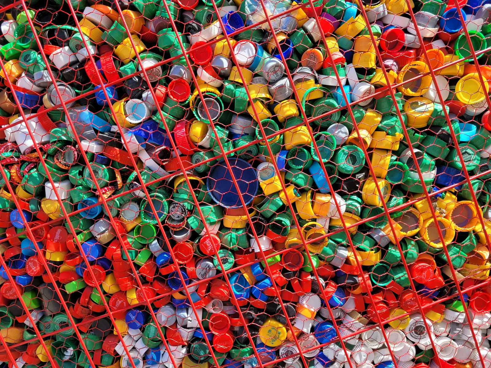 Betriebsmittelprüfung und Leiter- und Trittprüfung in der Kunststoffverarbeitung: Kunststoffdeckel hinter einem Gitter.