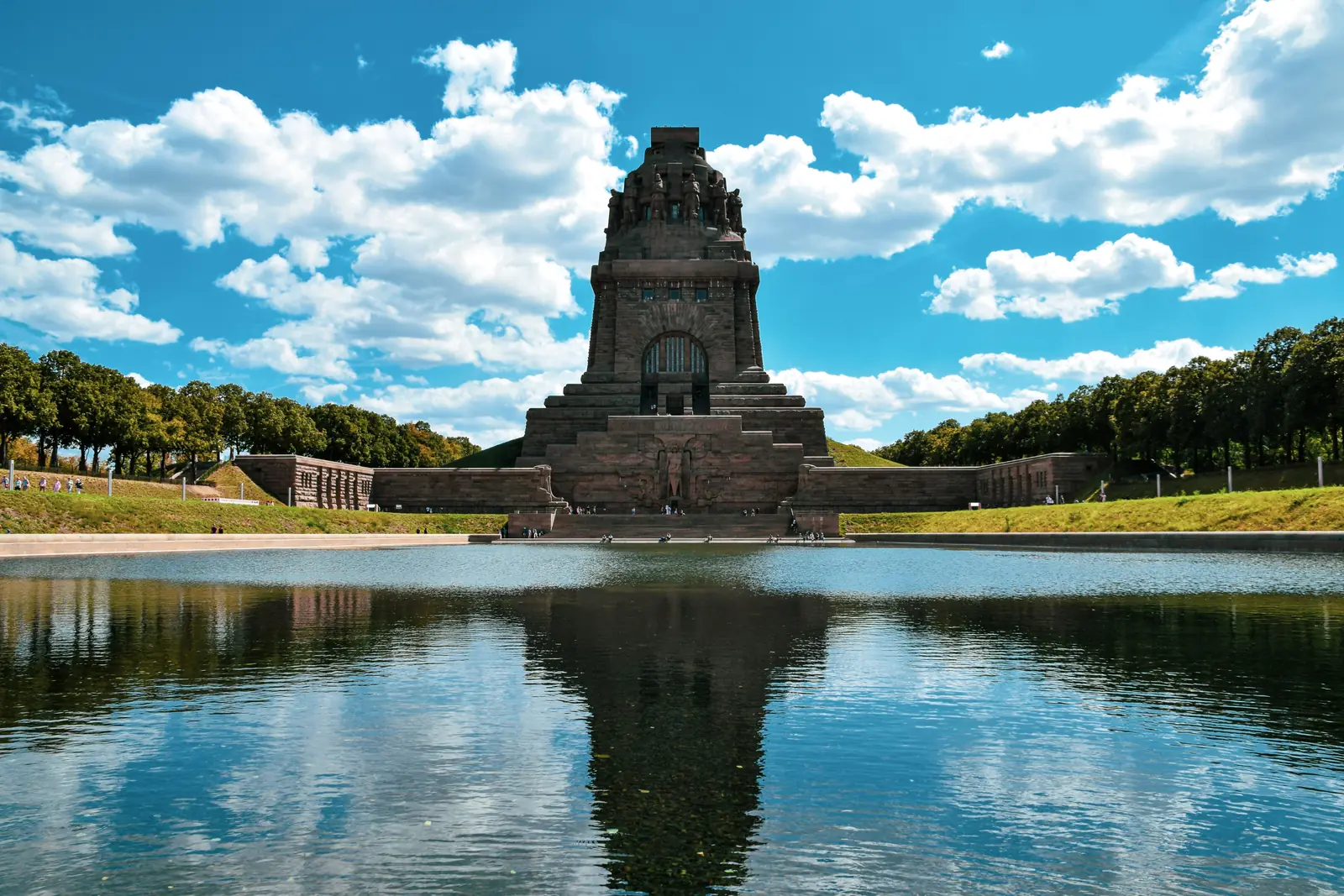 Betriebsmittelprüfung und Leiter- und Trittprüfung in Leipzig: Steinernes Denkmal mit Spiegelung im Wasserbecken.