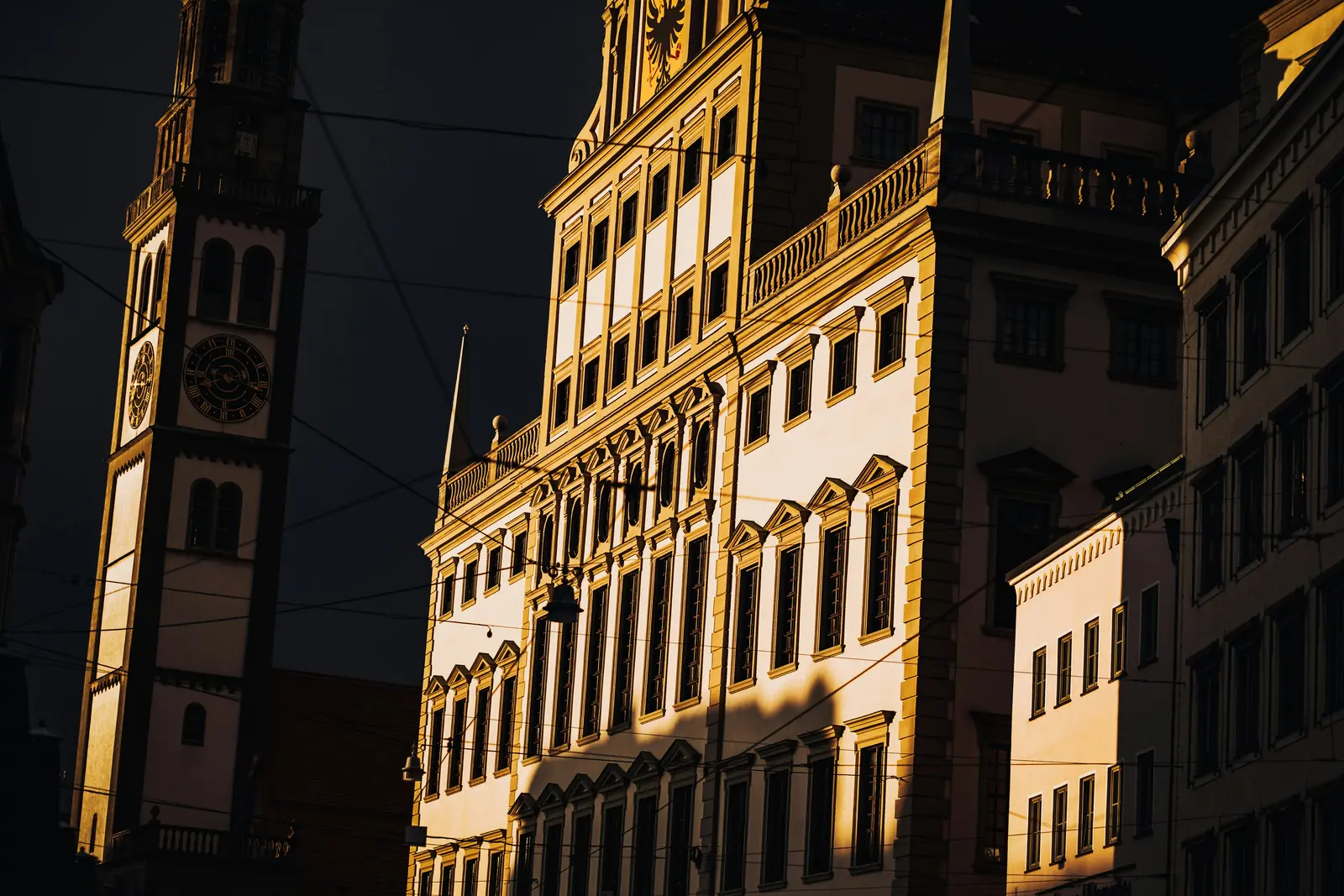 Leiter- und Trittprüfung in Augsburg: Hohe Fassade und Turm im Abendlicht.