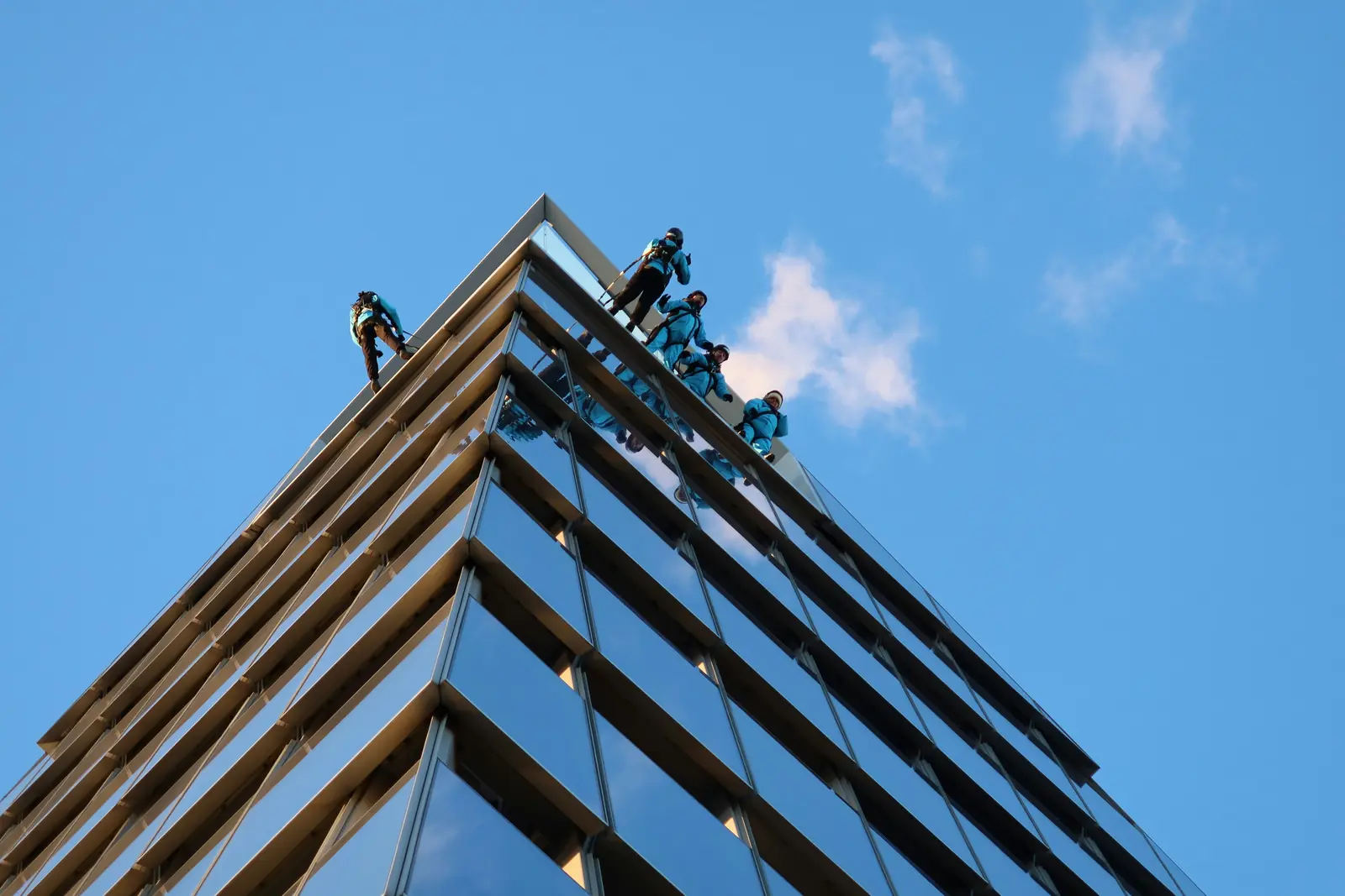Leiter- und Trittprüfung im Facility Management: Höhenarbeiter auf dem Dach eines Glasgebäudes.