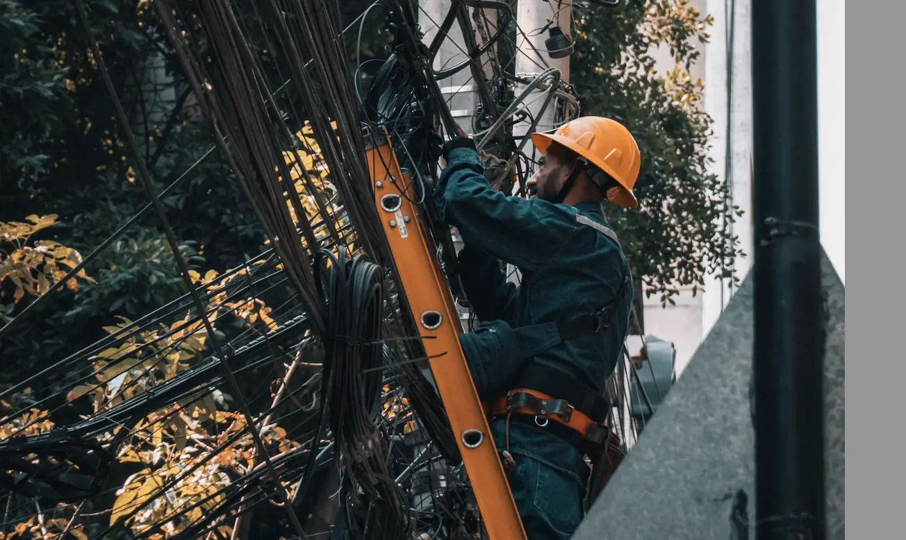Leiter- und Trittprüfung in Gütersloh: Monteur auf einer Anlegeleiter am Kabelmast.