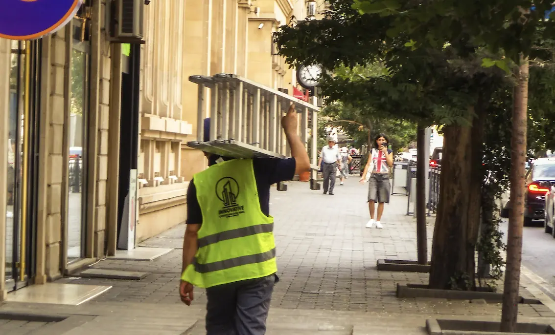 Leiter- und Trittprüfung in Moers: Handwerker trägt eine Aluleiter über der Schulter.
