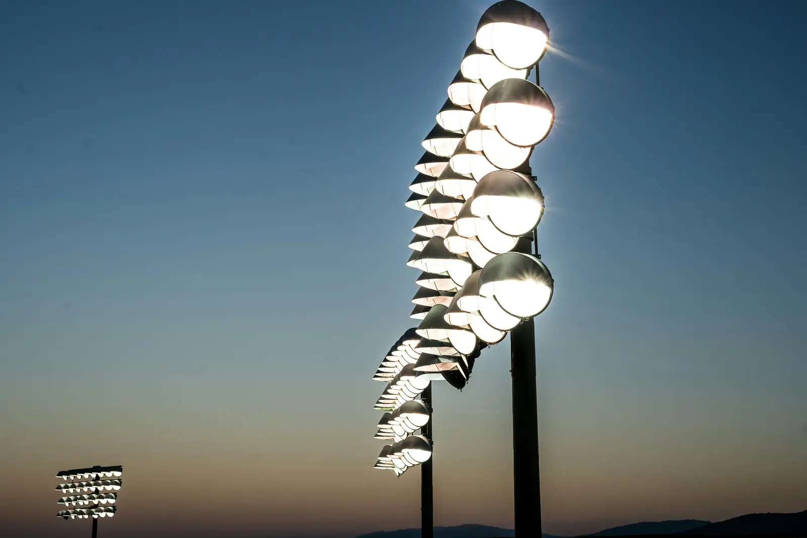Leiter- und Trittprüfung im Stadion: Flutlichtmasten mit Scheinwerfern in der Dämmerung.