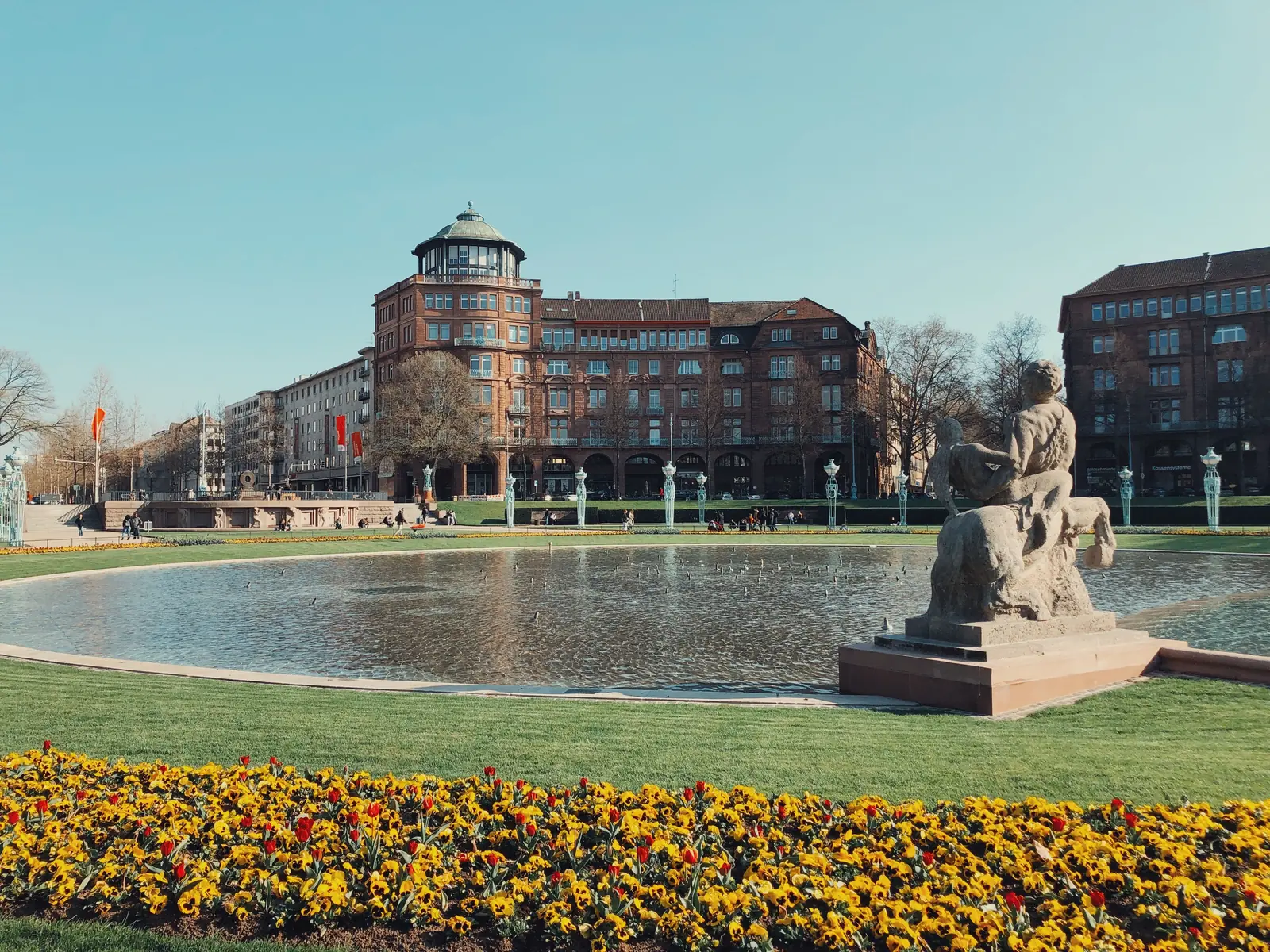 Betriebsmittelprüfung und Leiter- und Trittprüfung in Mannheim: Wasserbecken und Blumenbeet vor Kontorhäusern.