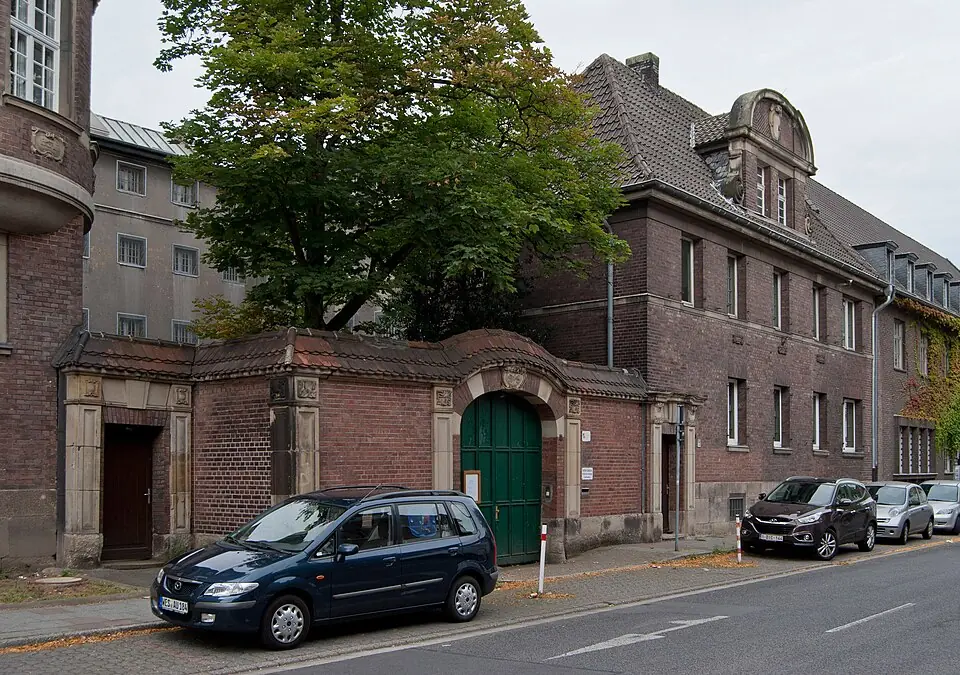Betriebsmittelprüfung und Leiter- und Trittprüfung in Moers: Backsteintor und Wohnhäuser an der Straße.
