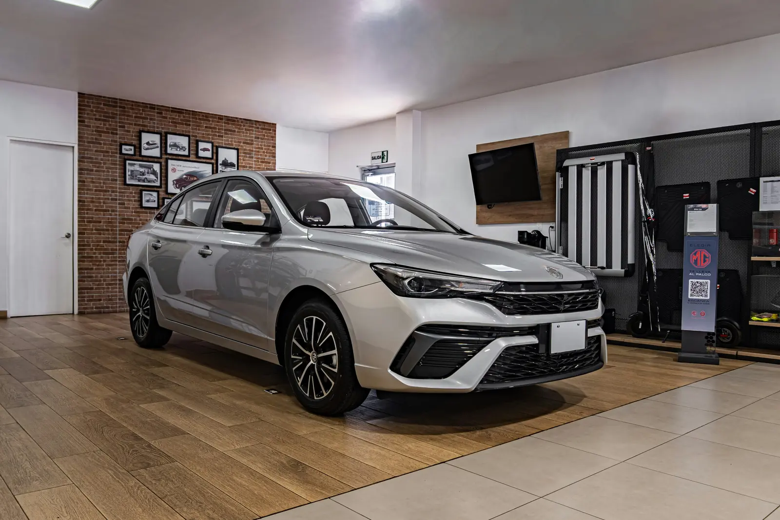 Betriebsmittelprüfung und Leiter- und Trittprüfung im Autohaus: Neuwagen im Showroom mit Wandmonitor und Zubehörregal.