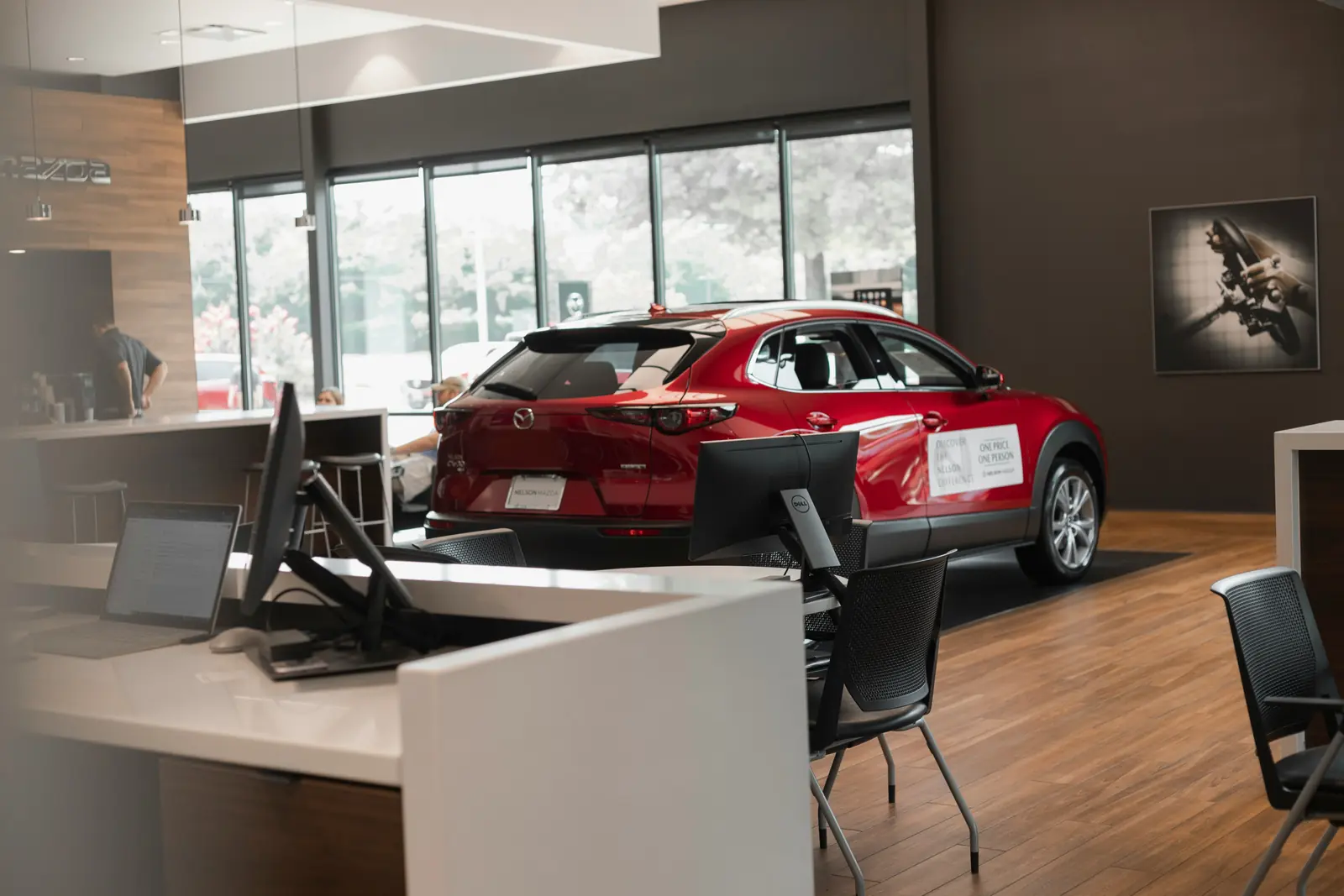 Betriebsmittelprüfung und Leiter- und Trittprüfung im Autohaus: Verkaufsraum mit Beratungsplätzen, Monitoren und Neuwagen.