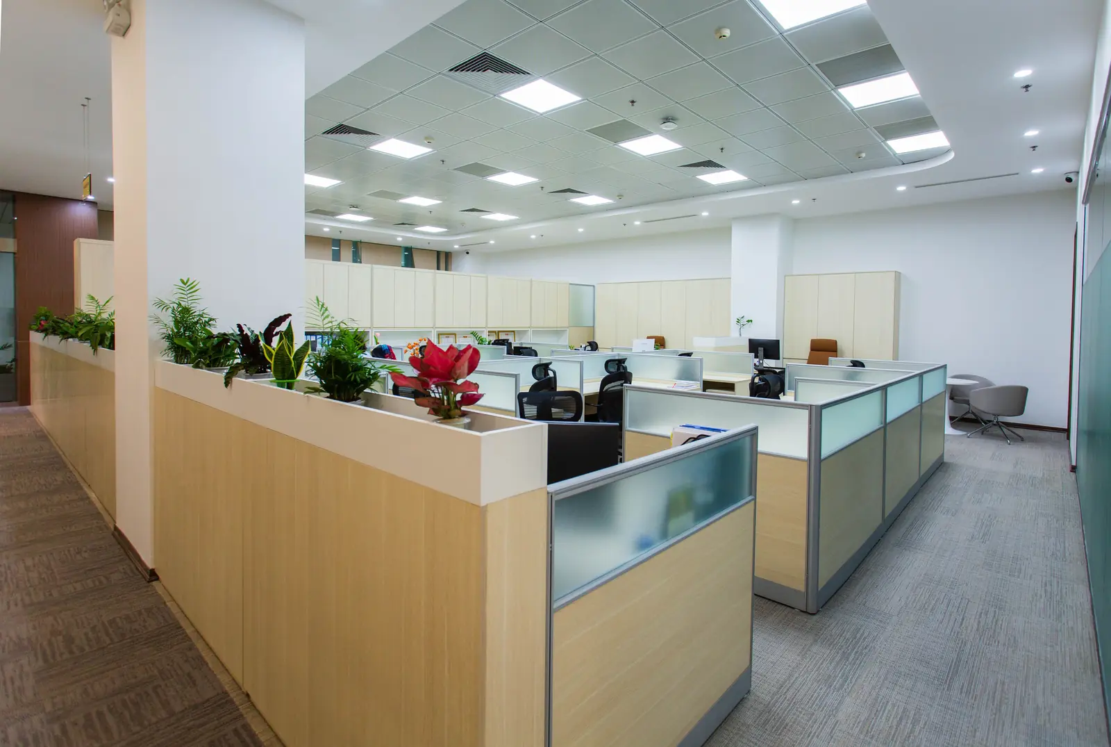 Betriebsmittelprüfung und Leiter- und Trittprüfung in der Bank: Großraumbüro mit Deckenleuchten und Arbeitsplätzen.