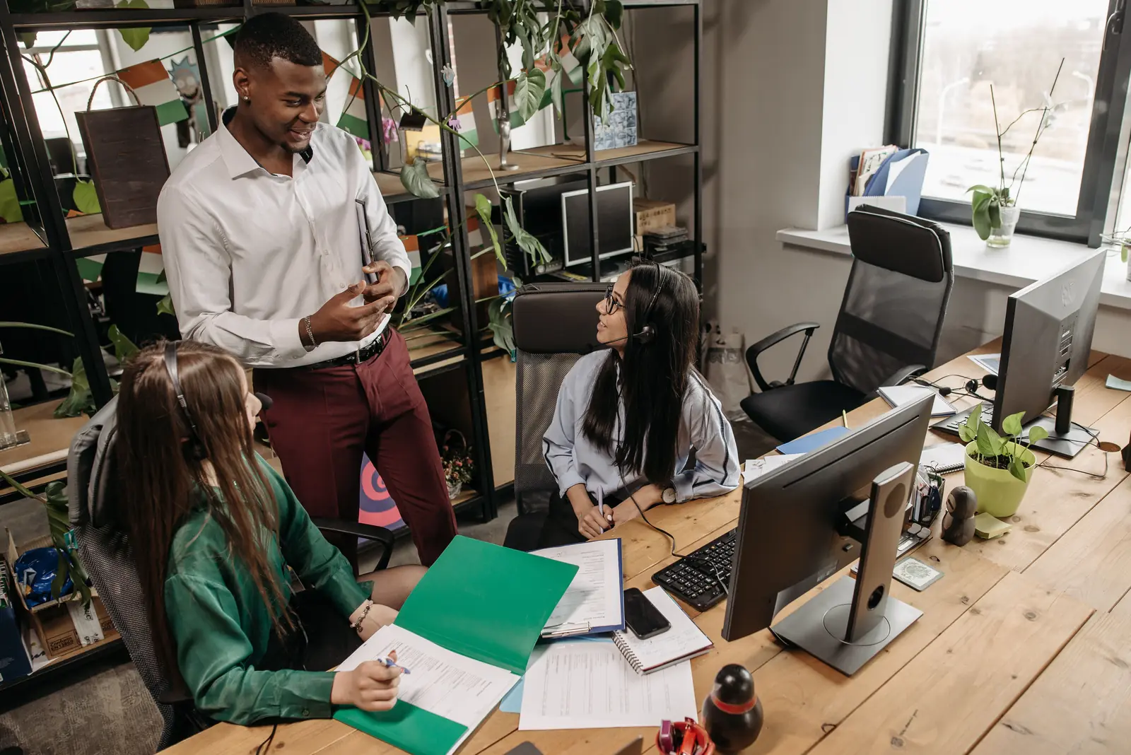 Betriebsmittelprüfung und Leiter- und Trittprüfung im Callcenter: Gespräch am Arbeitsplatz mit Monitor und Unterlagen.
